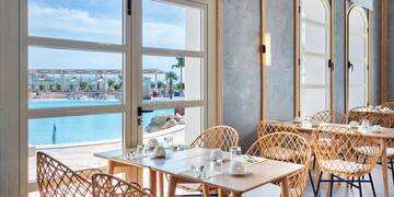 a table and chairs in a room with a view of water and a beach