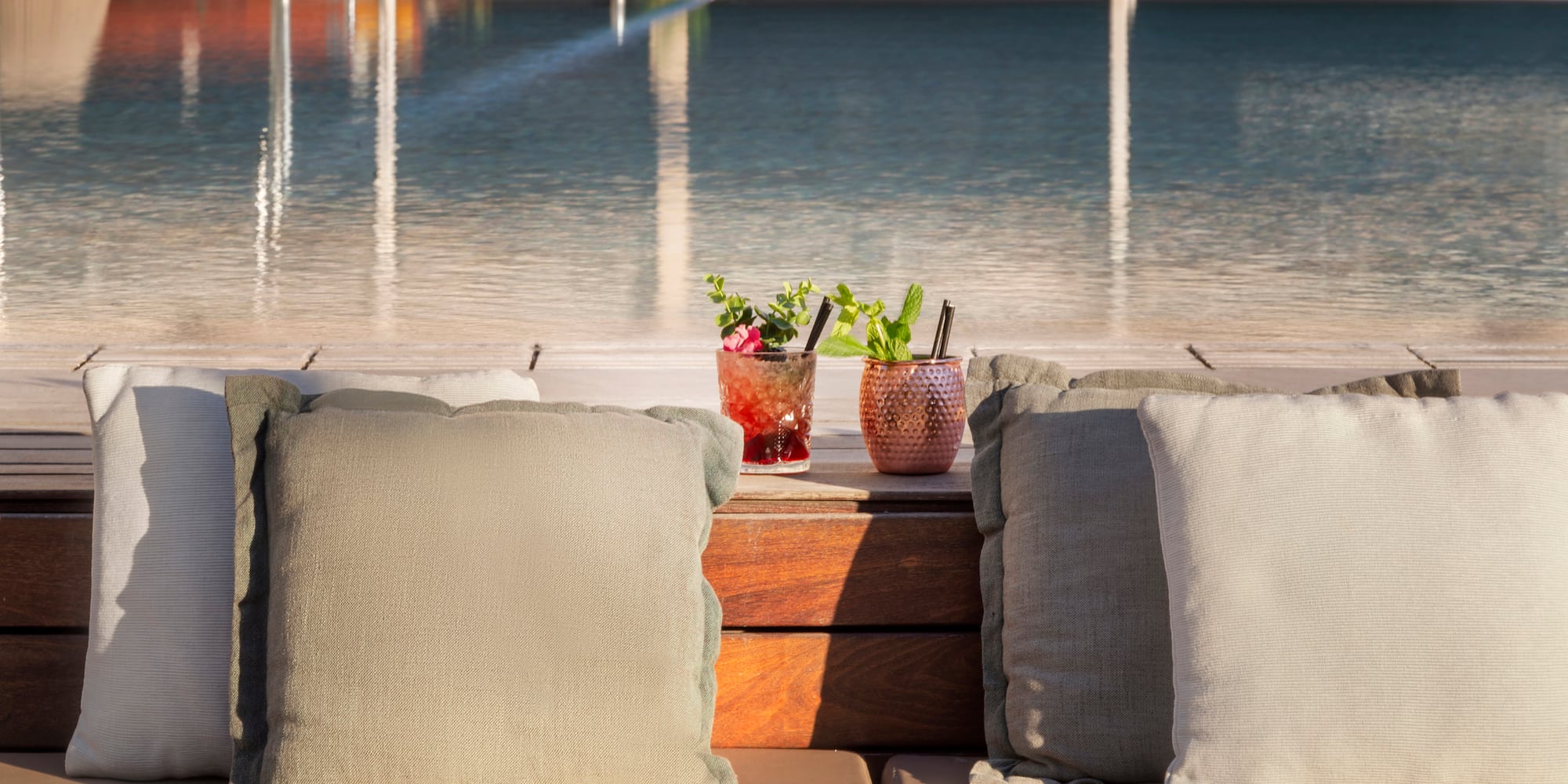 a two pillows on a table next to a pool