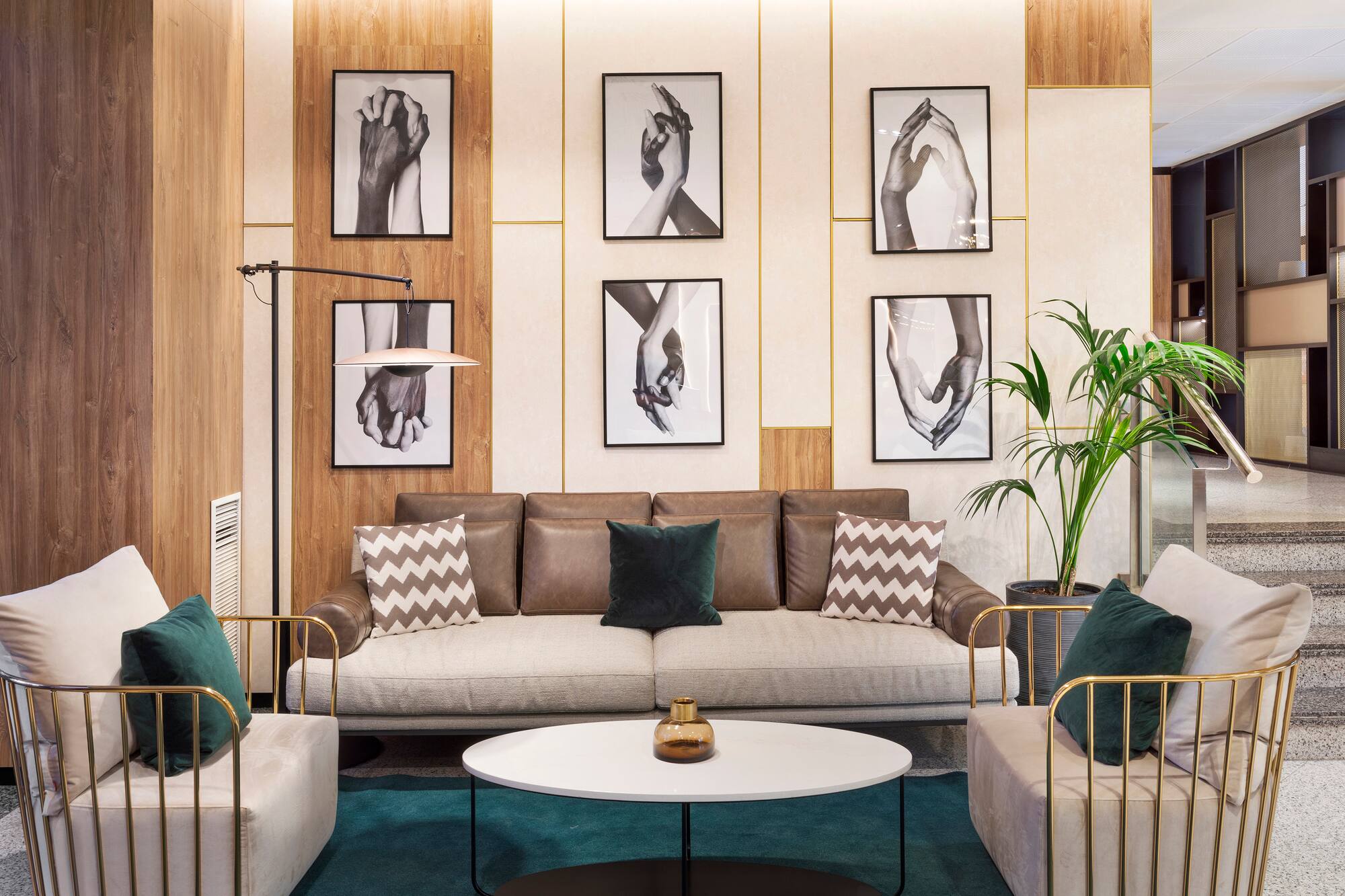 Modern hotel lobby lounge with sofa, armchairs, and framed hand art decor.
