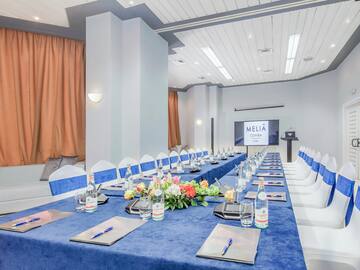 a long table with blue tablecloths and flowers on it