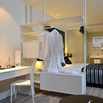 a room with a bed and a white robe on a rack