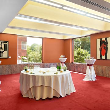 a room with a round table with white tablecloths and wine bottles