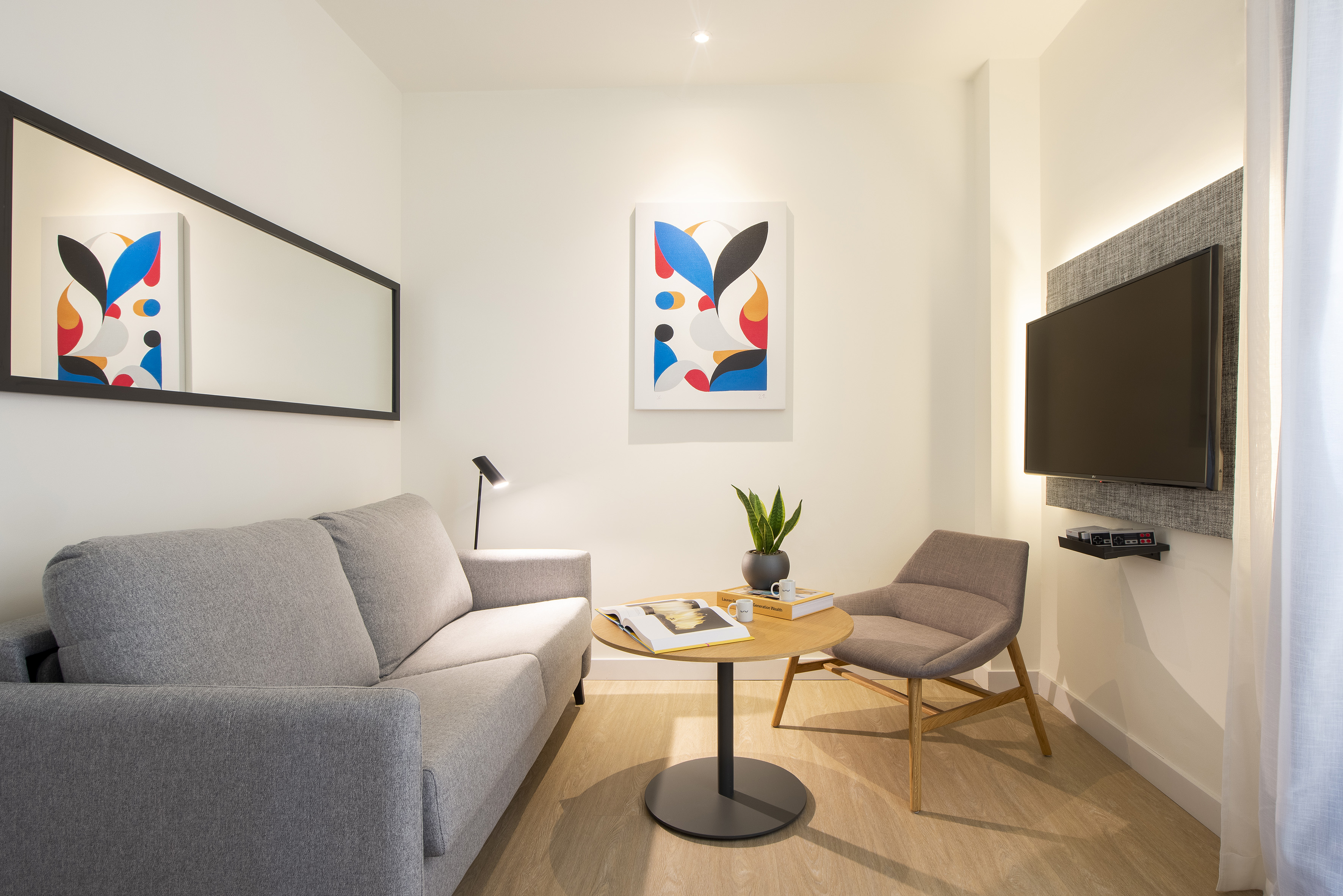 Contemporary lounge with gray sofa, flat-screen TV, and colorful abstract art.
