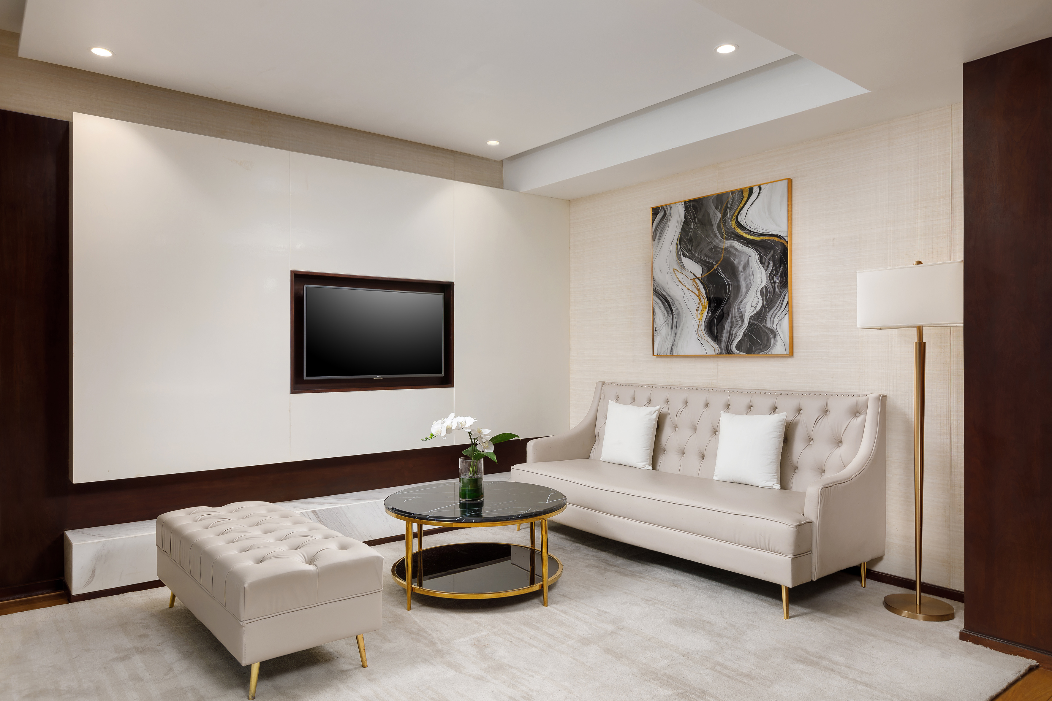 Modern living room with beige sofa, TV, coffee table, and abstract wall art.