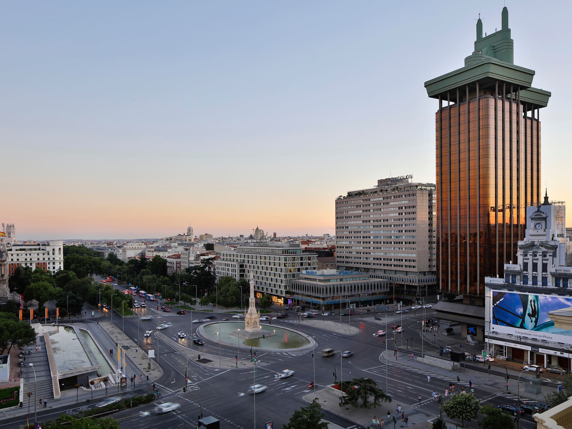 a city street with a fountain and buildings