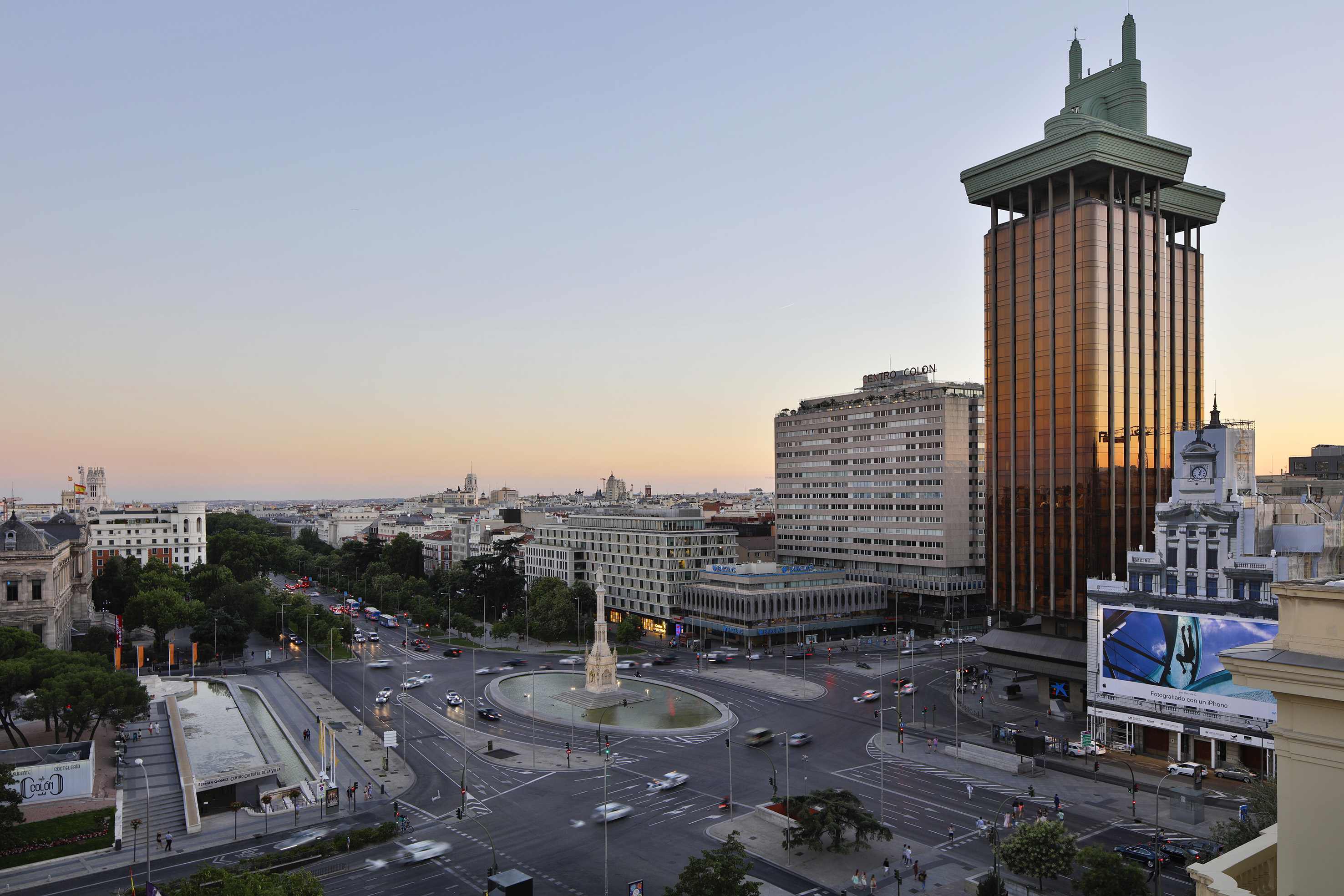 a city street with a fountain and buildings