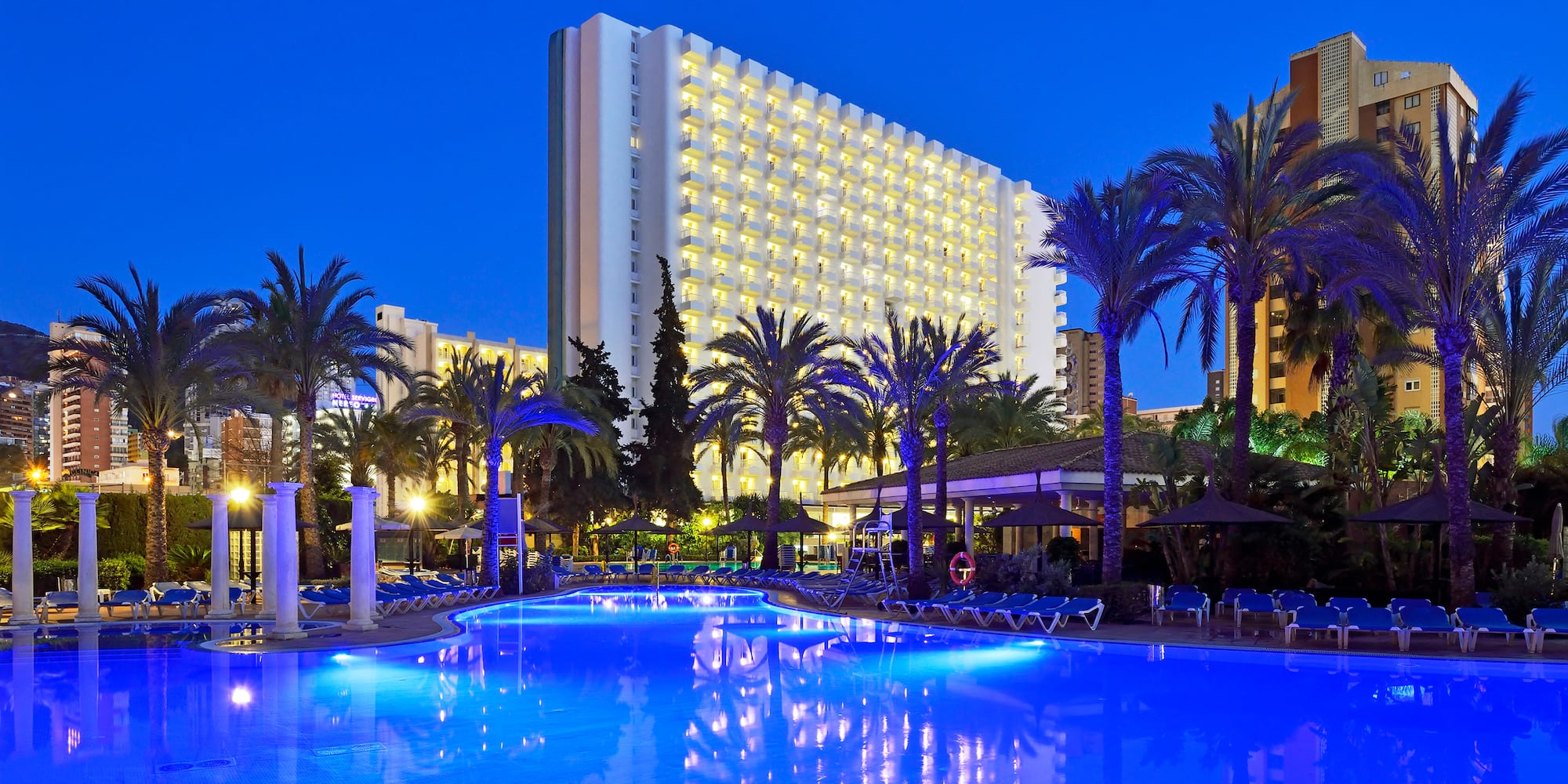 a pool with palm trees and a building in the background