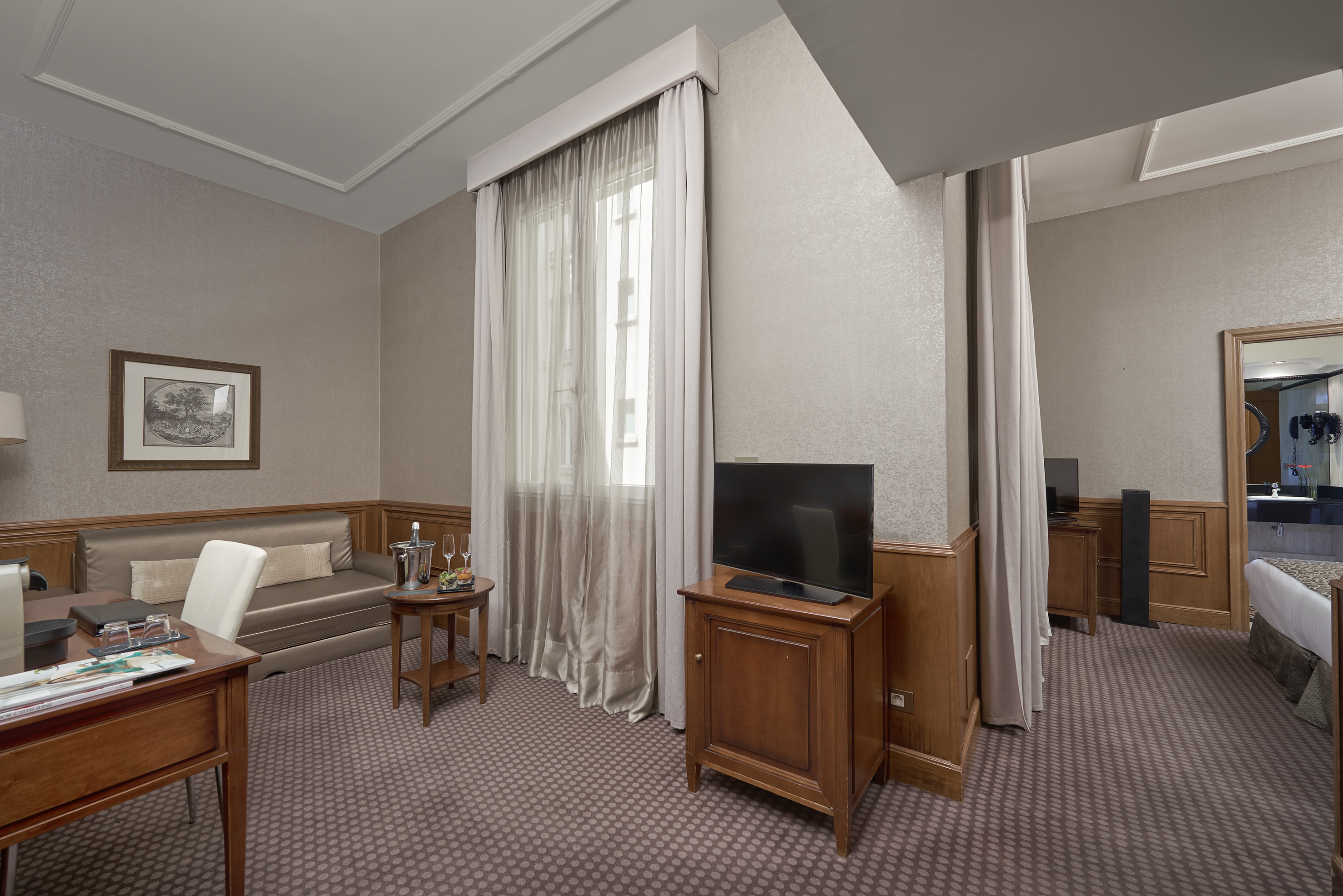 Luxury hotel suite living area with sofa, modern TV, and elegant decor.