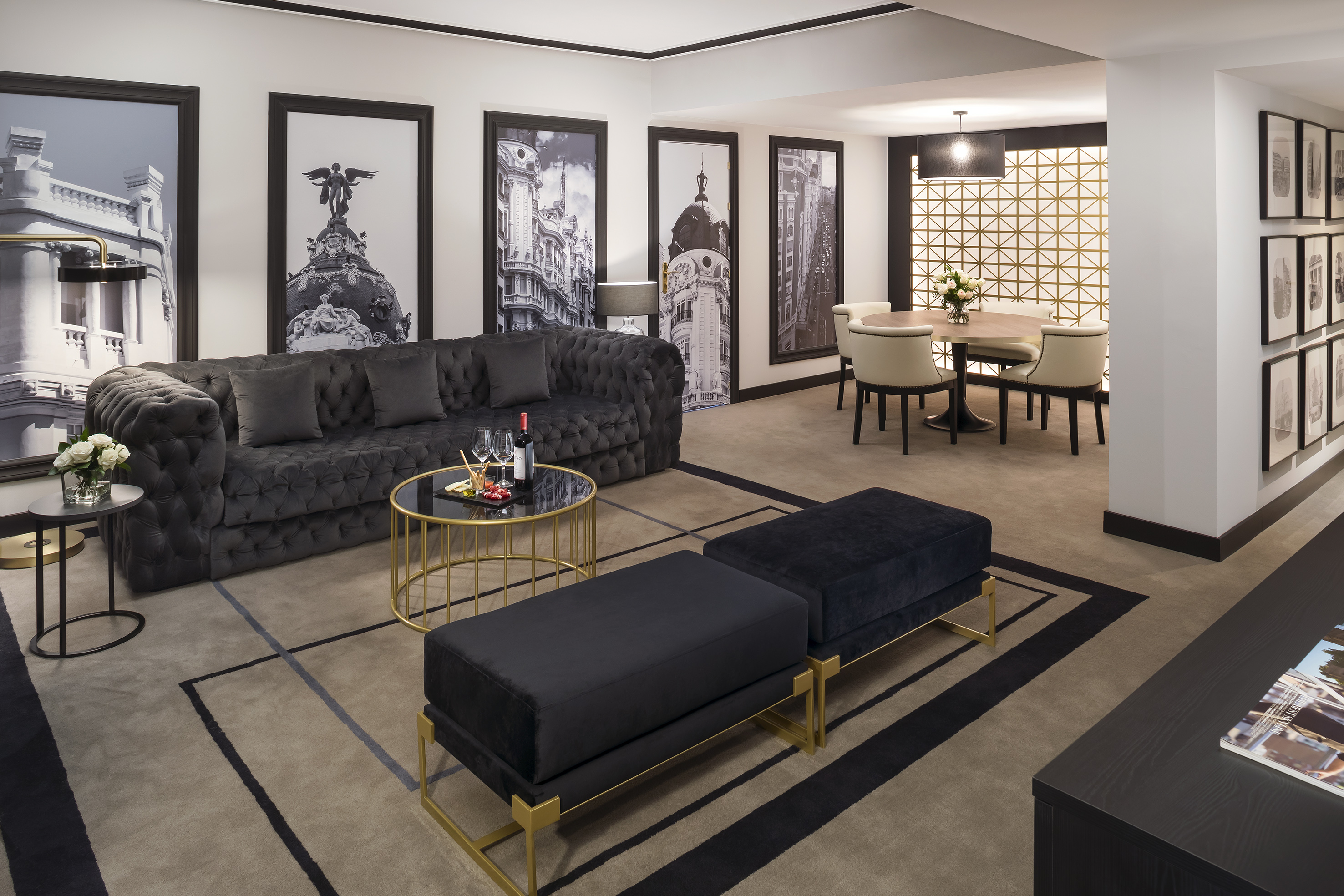 Luxury suite with dark velvet sofa, gold accents, and framed cityscape art.