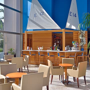 a bar with tables and chairs in a room with a blue wall