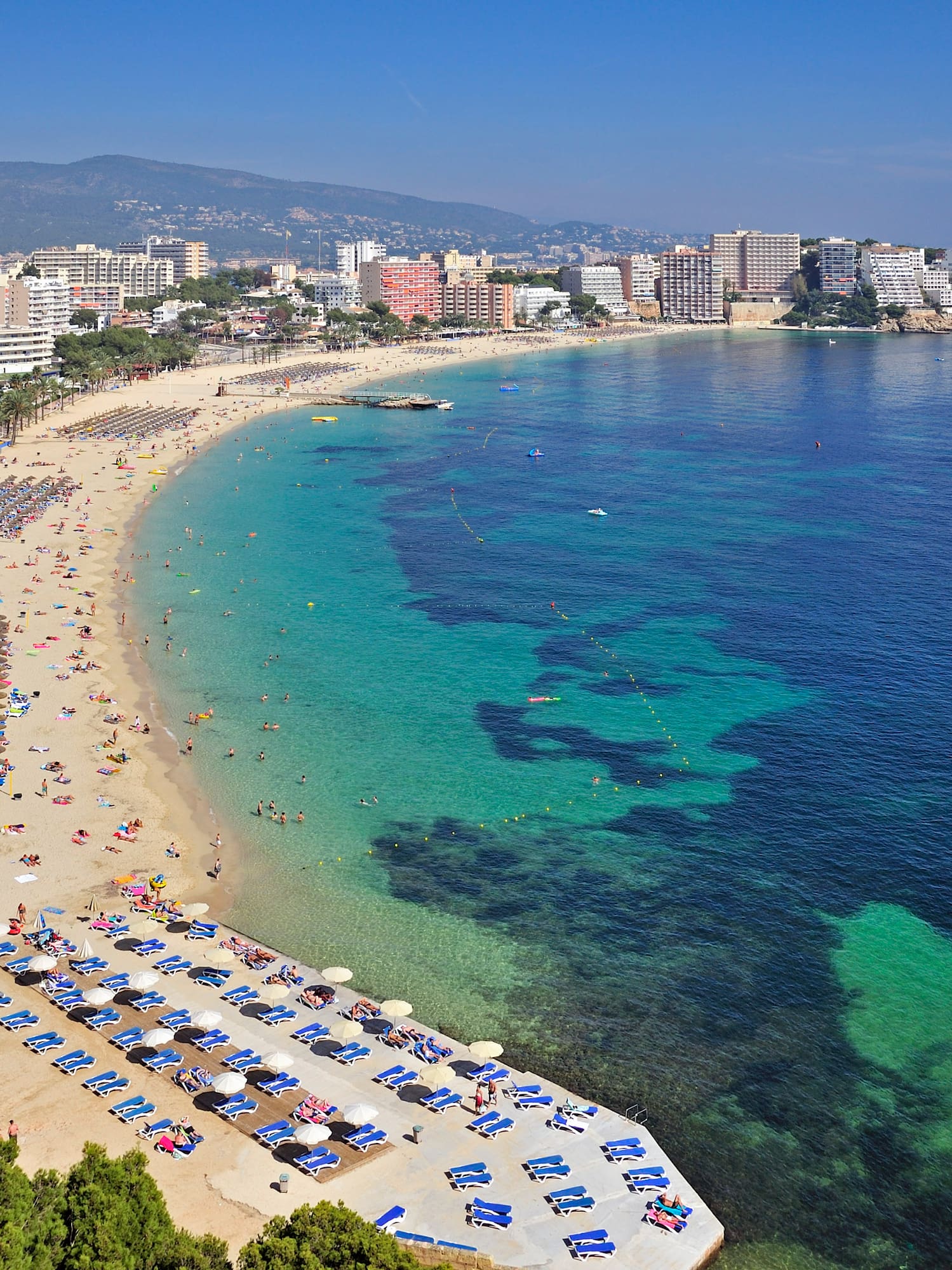 a beach with many umbrellas and chairs and buildings