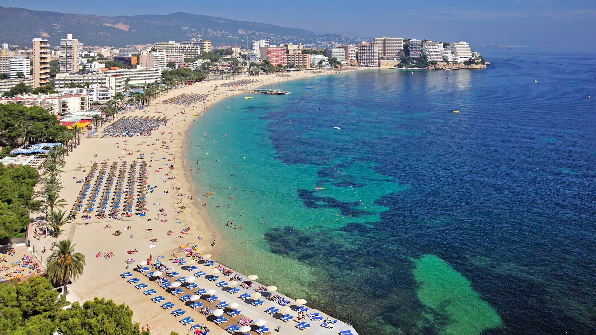 a beach with many umbrellas and chairs and buildings