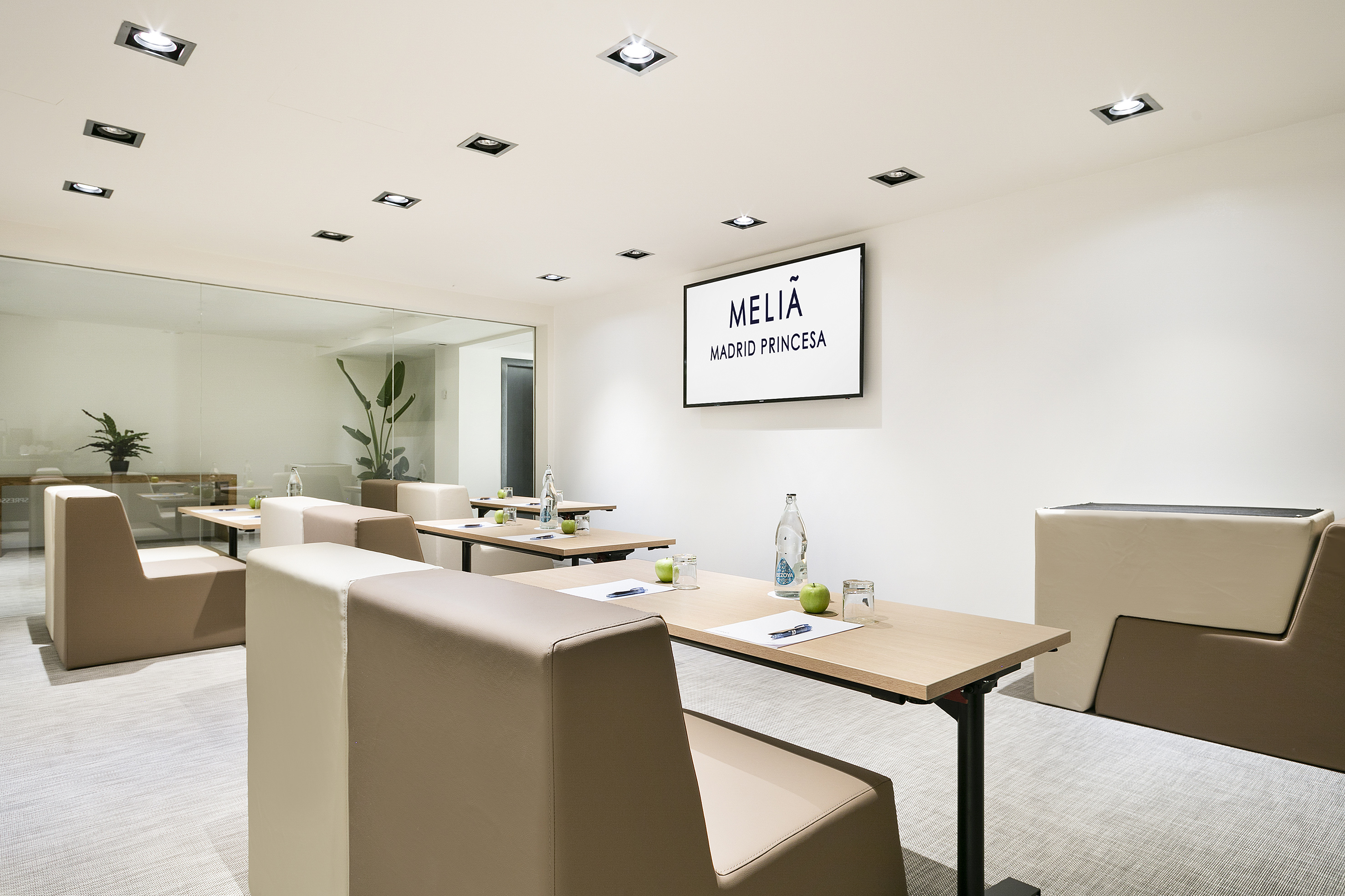 Modern meeting room at Meliá Madrid Princesa with tables, seating, and TV screen.