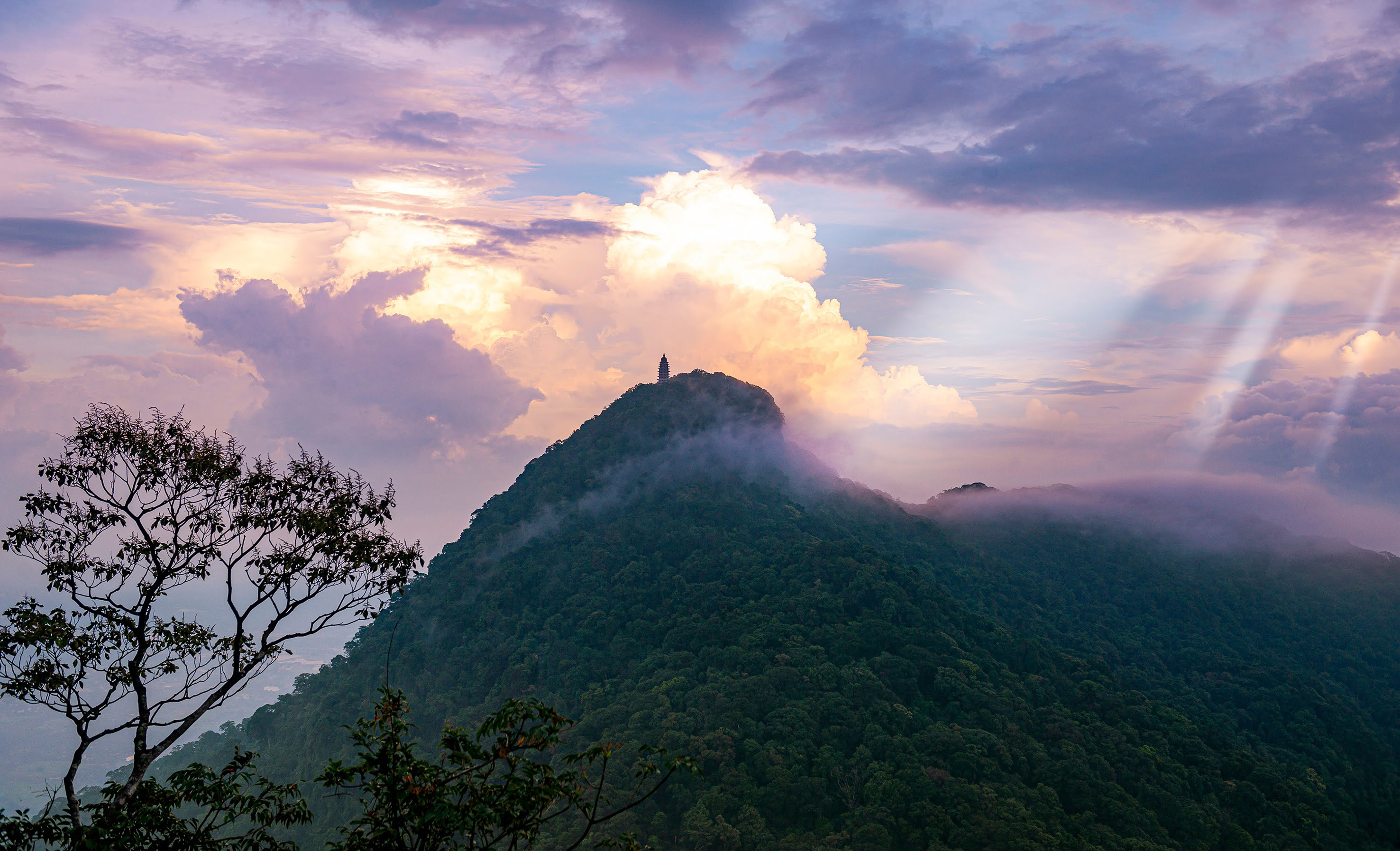 a mountain with clouds and a tower on top