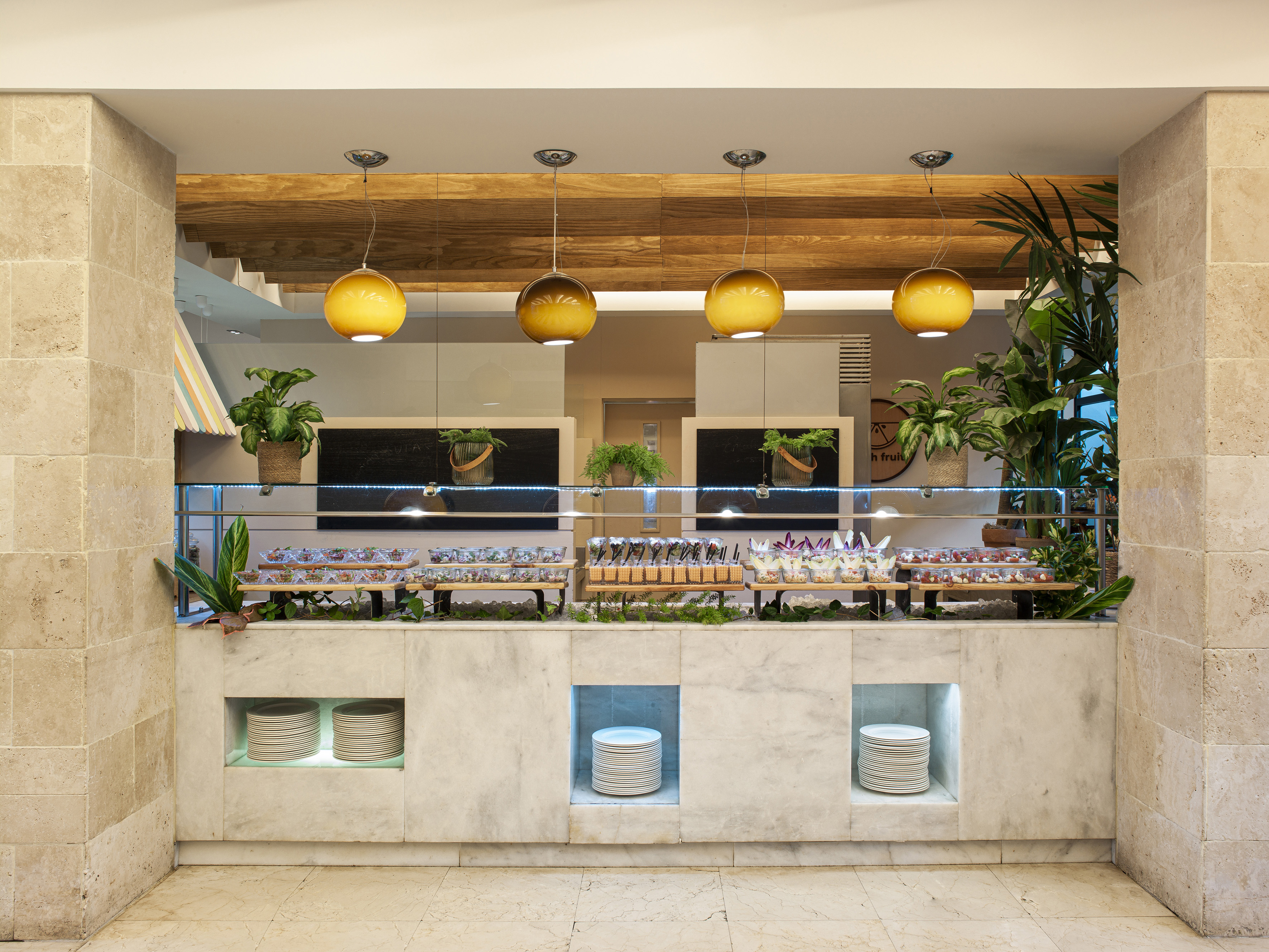 Marble buffet with individual desserts, stacked plates, and globe pendant lights.