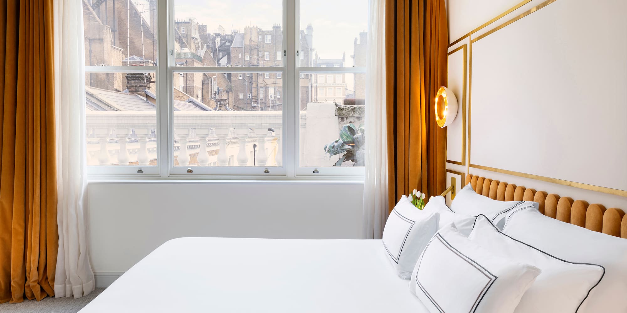 a bed with white sheets and pillows in a room with windows
