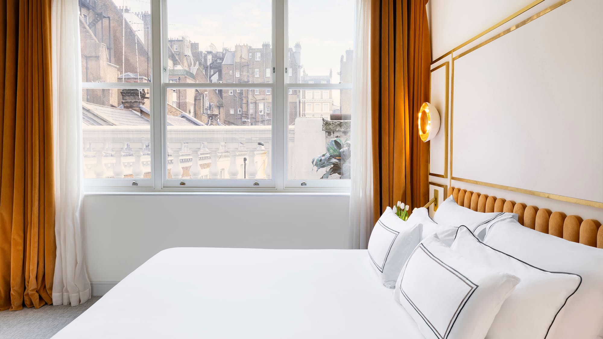 a bed with white sheets and pillows in a room with windows