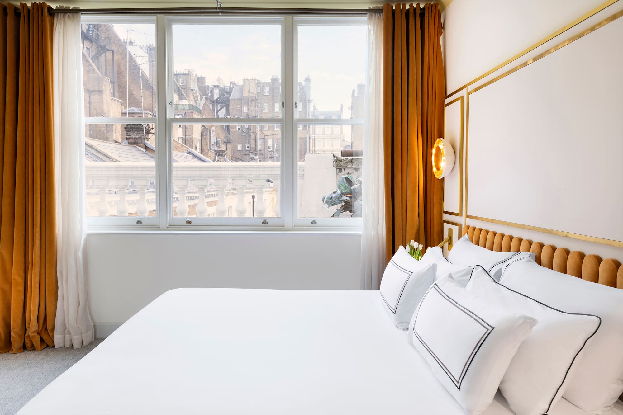 a bed with white sheets and pillows in a room with windows