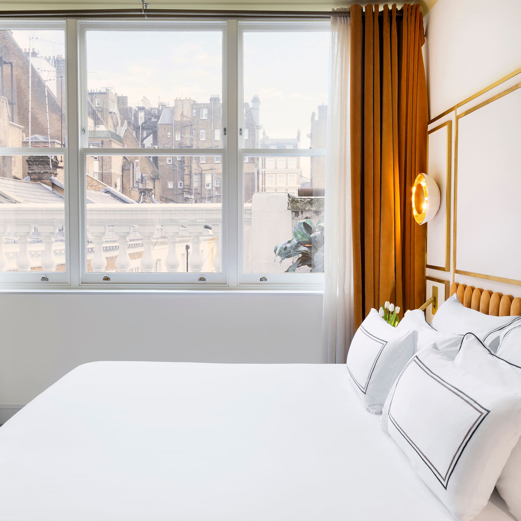 a bed with white sheets and pillows in a room with windows
