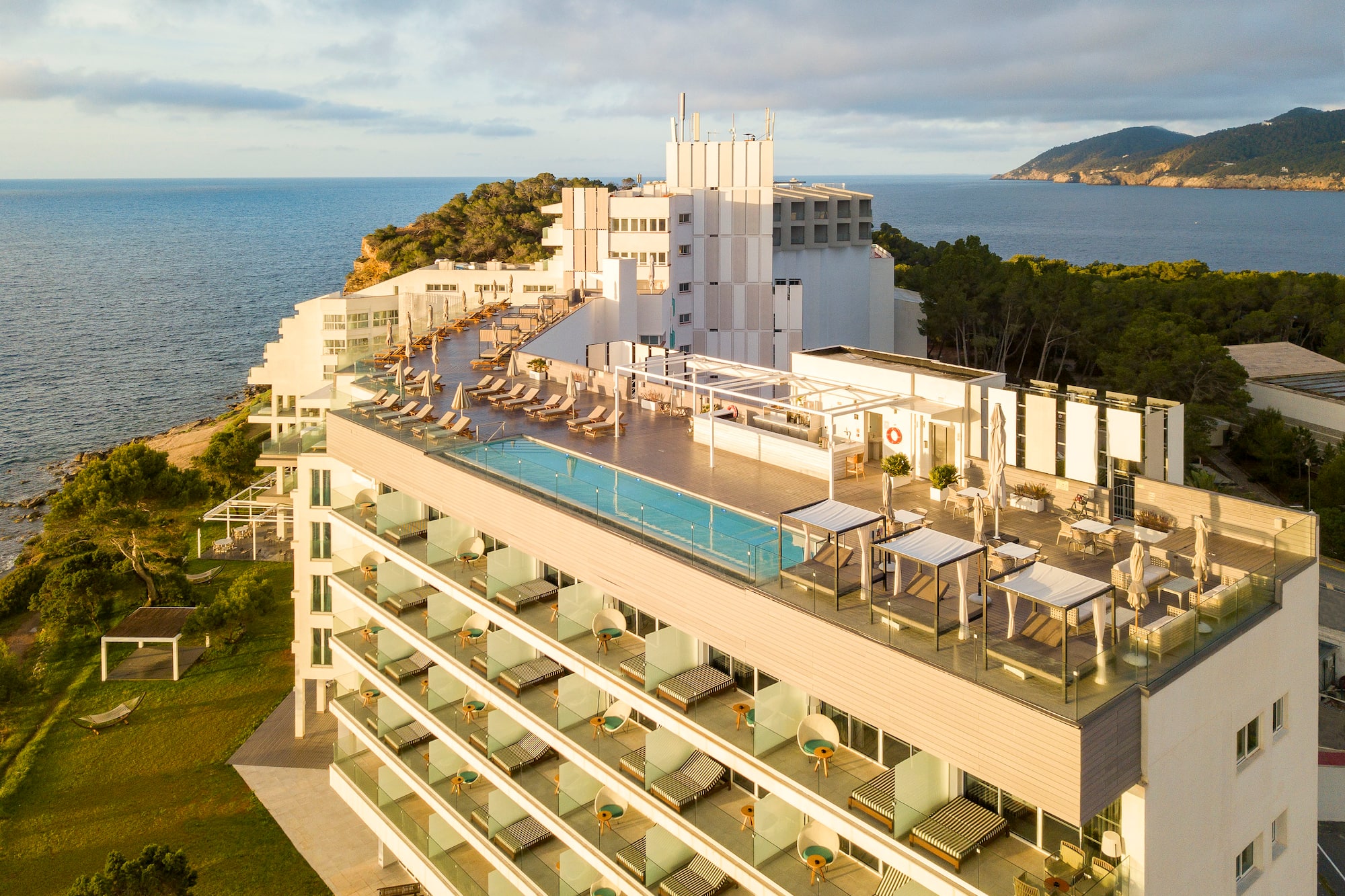 Modern coastal hotel with rooftop pool, balconies, and ocean views.