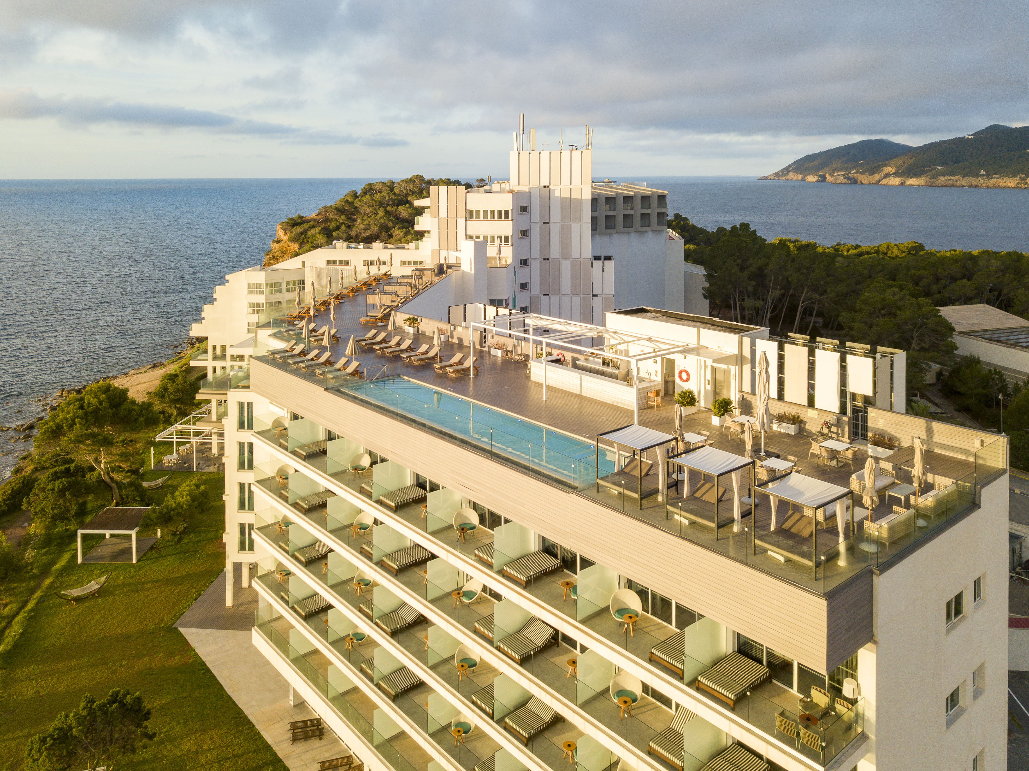 Modern coastal hotel with rooftop pool, balconies, and ocean views.