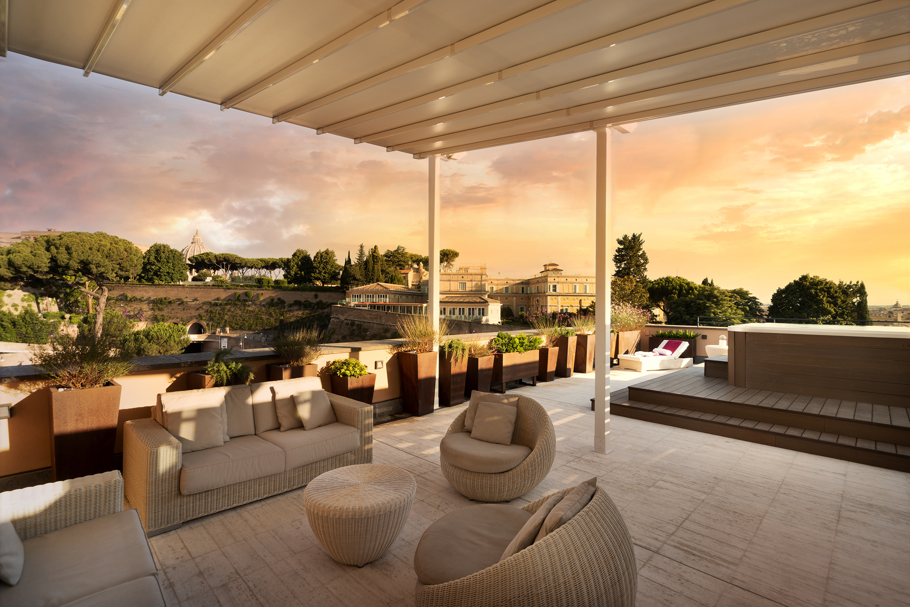 Rooftop terrace in Rome with sunset view, outdoor seating, and hot tub.