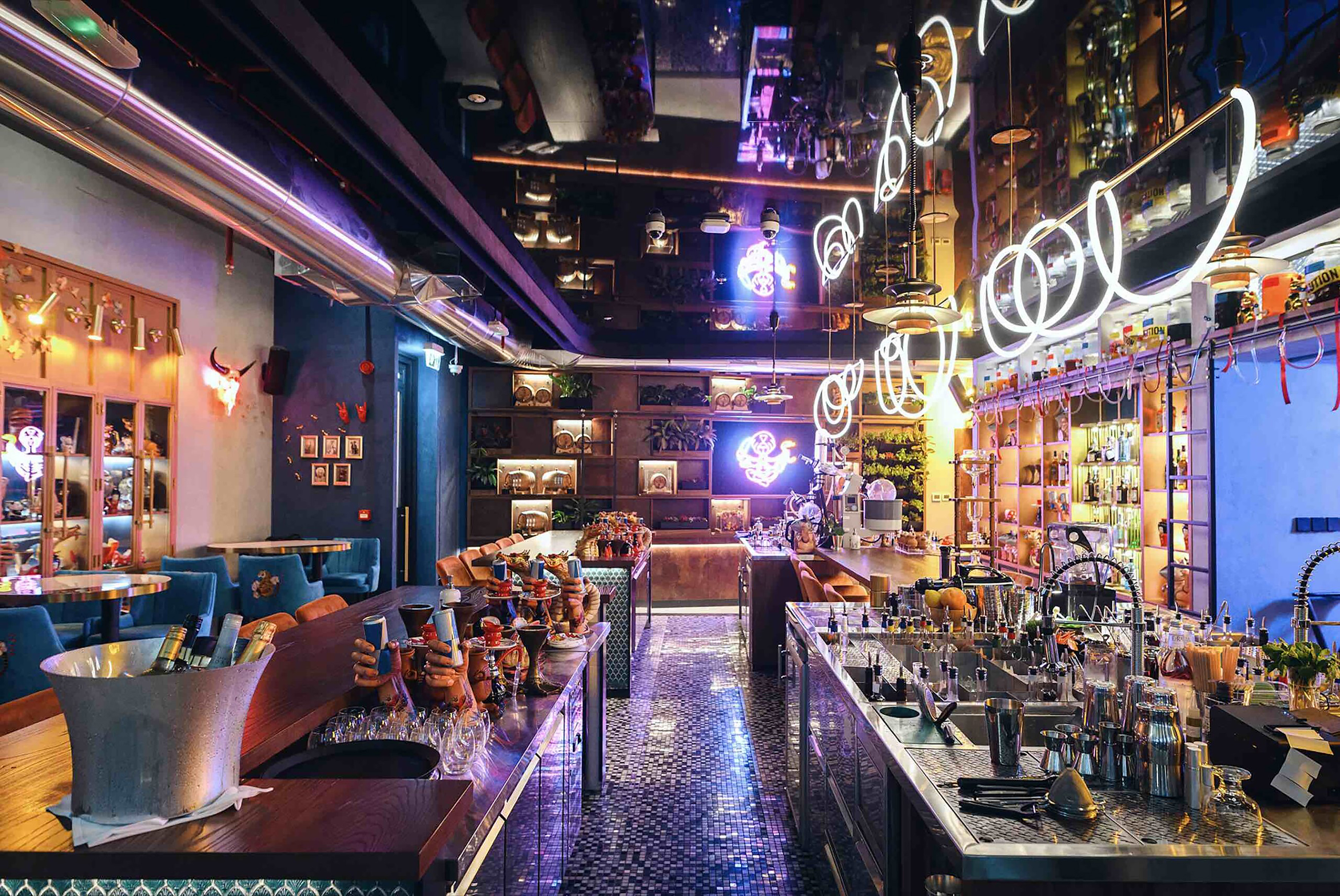 Vibrant bar interior with neon lights, mirrored ceiling, and cocktail counters.