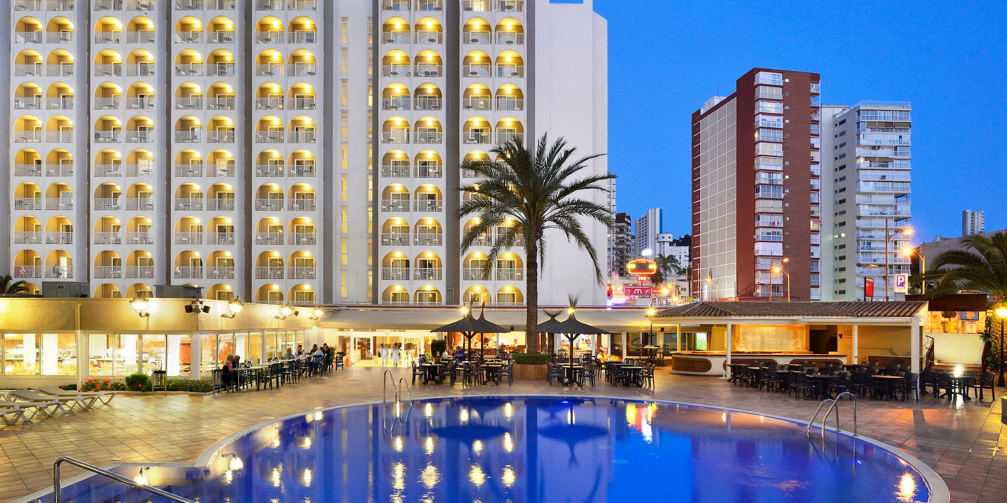 a pool with tables and chairs in front of a building