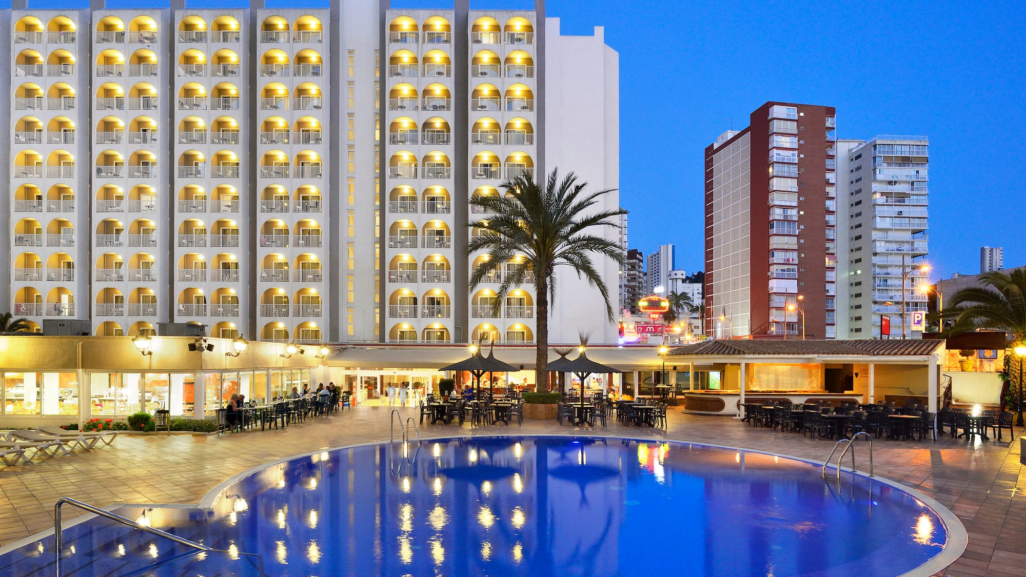 a pool with tables and chairs in front of a building