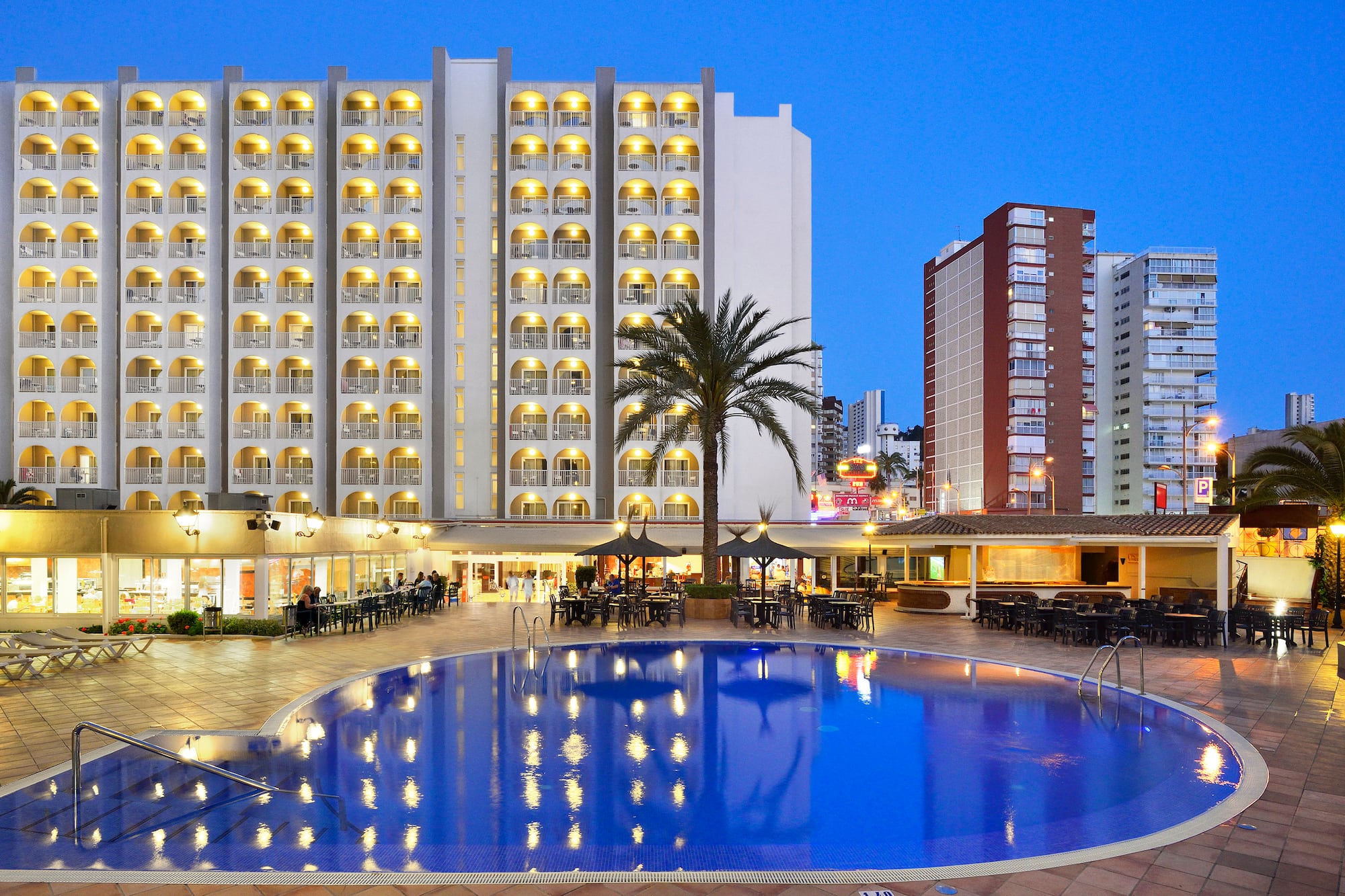 a pool with tables and chairs in front of a building