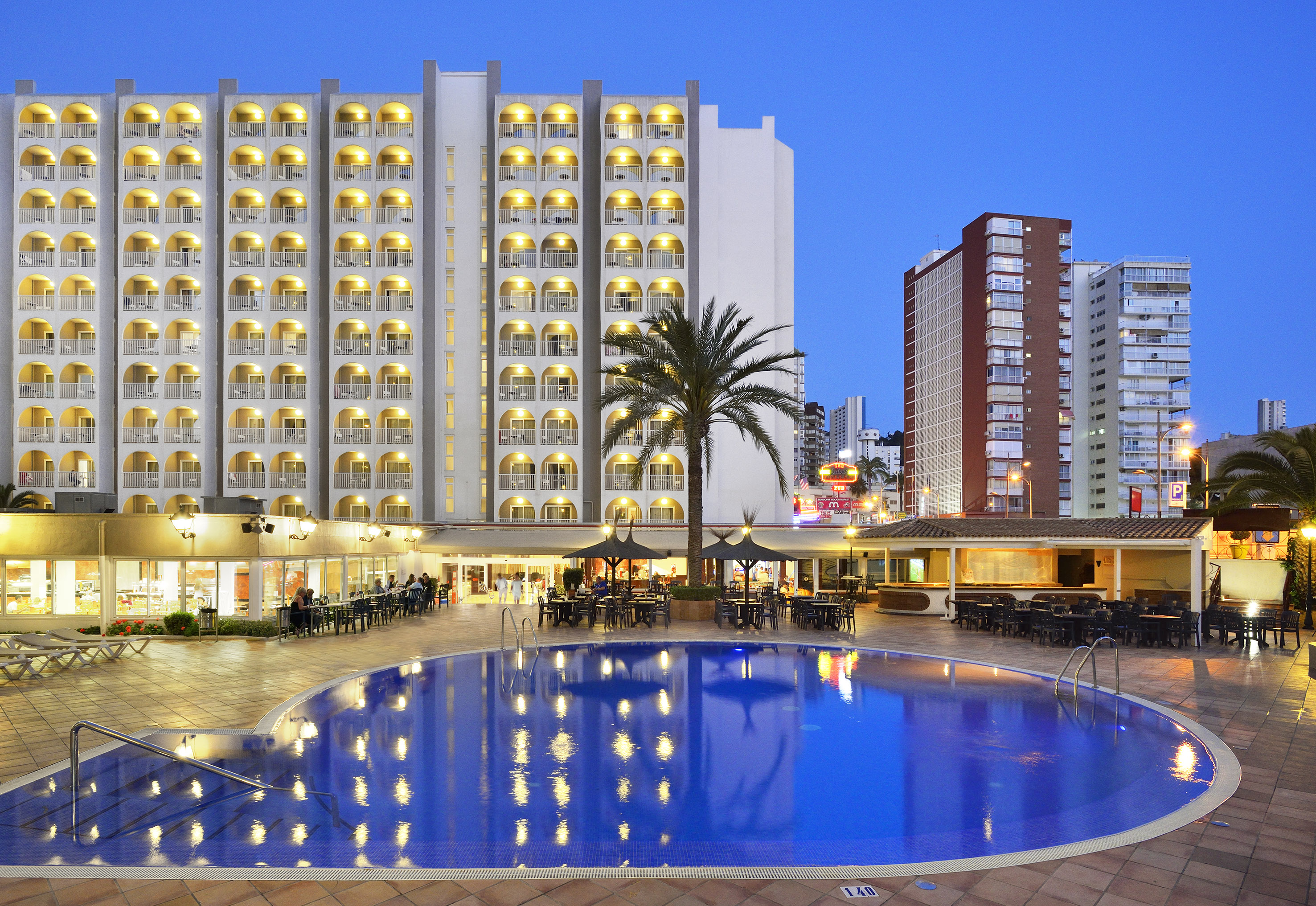 a pool with tables and chairs in front of a building