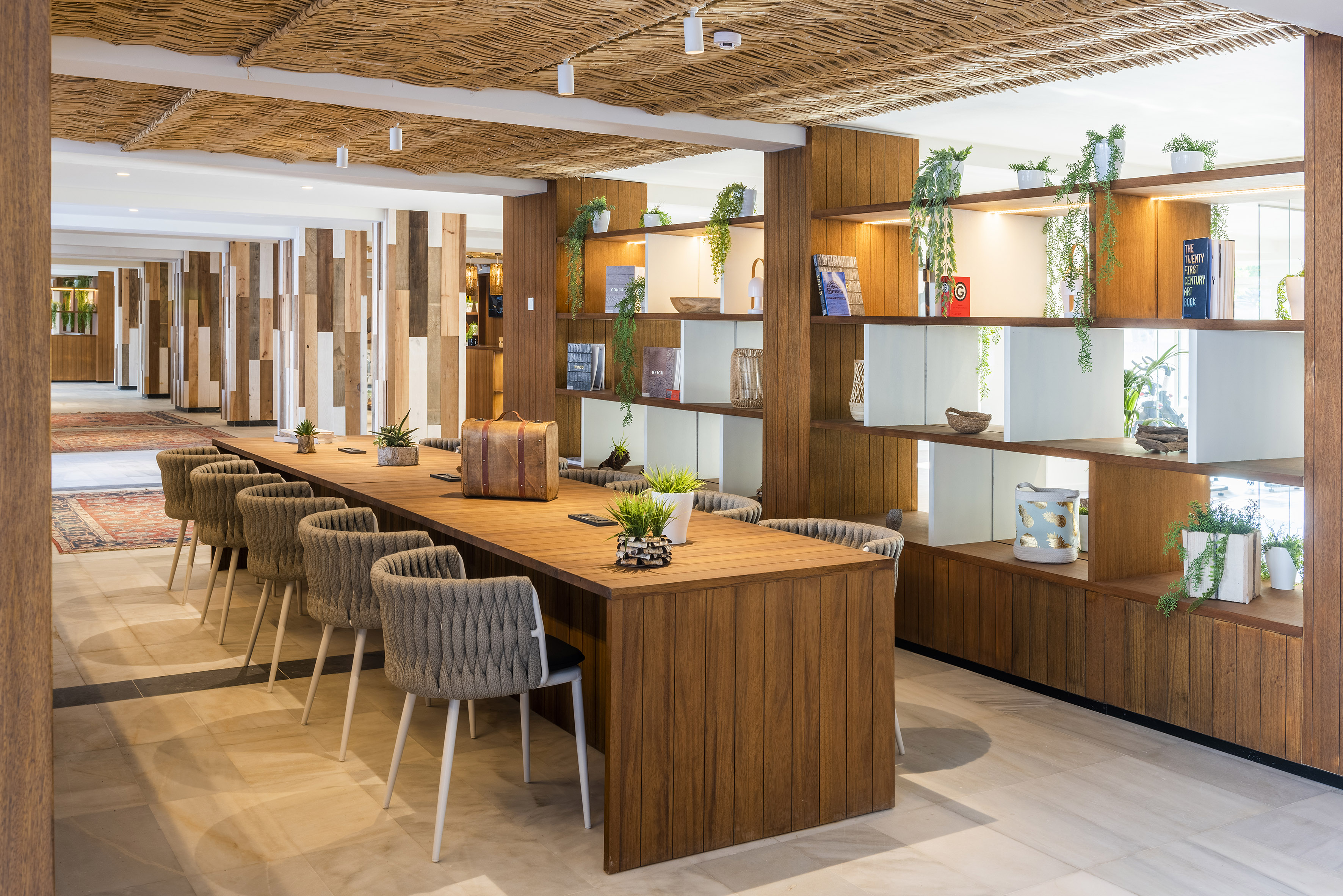 Modern co-working area with large wooden table, woven ceiling, and stylish decor.