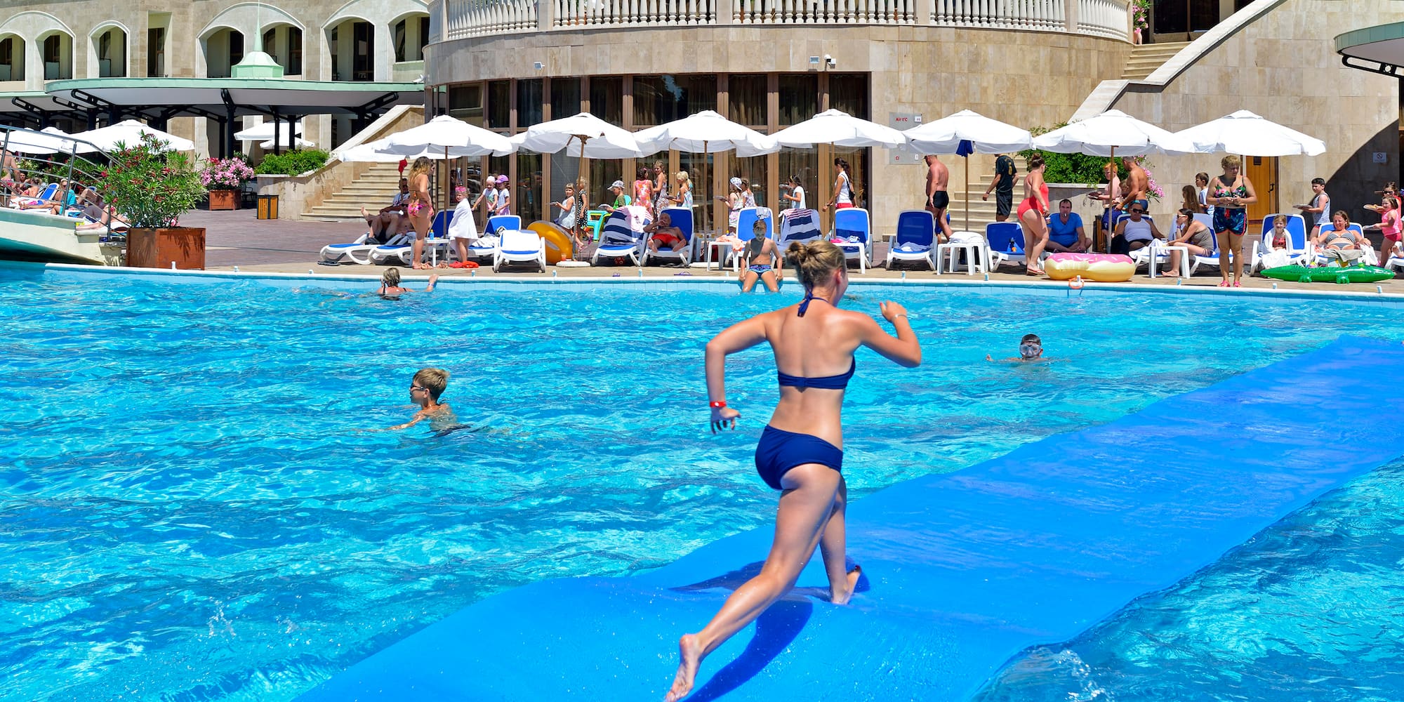a woman running on a floating mattress in a pool