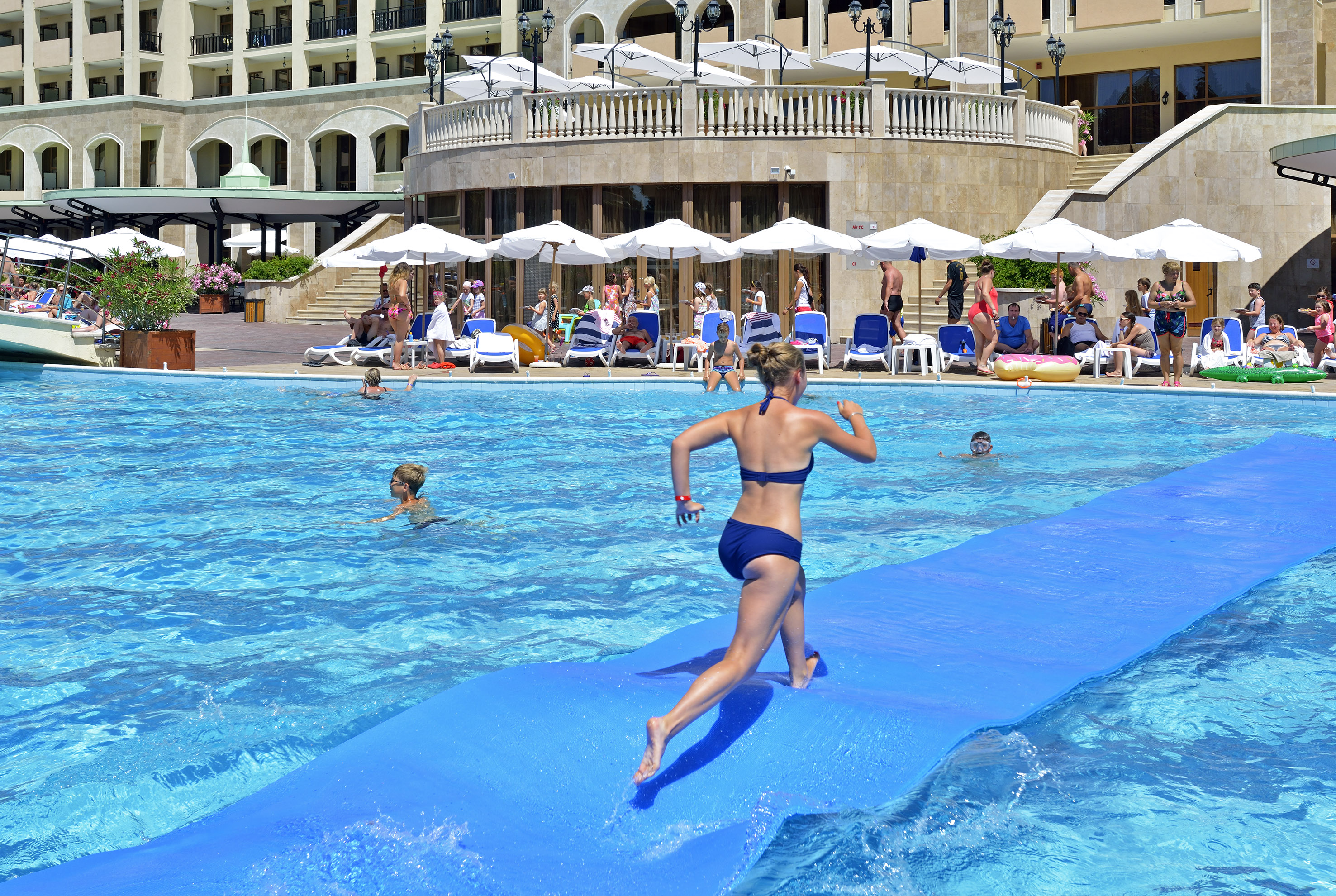 a woman running on a floating mattress in a pool
