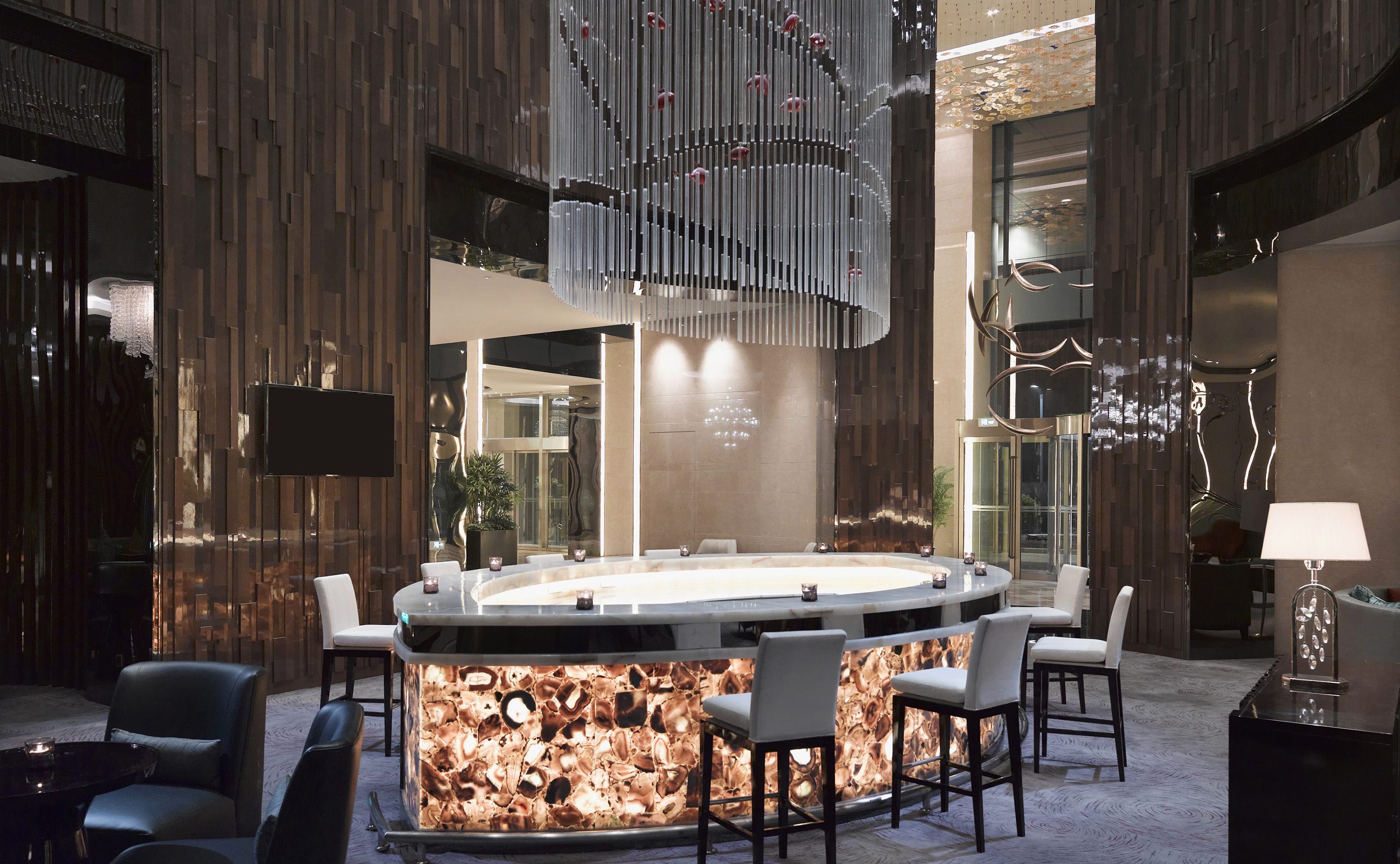 Luxury hotel lobby bar with backlit agate counter and modern chandelier.