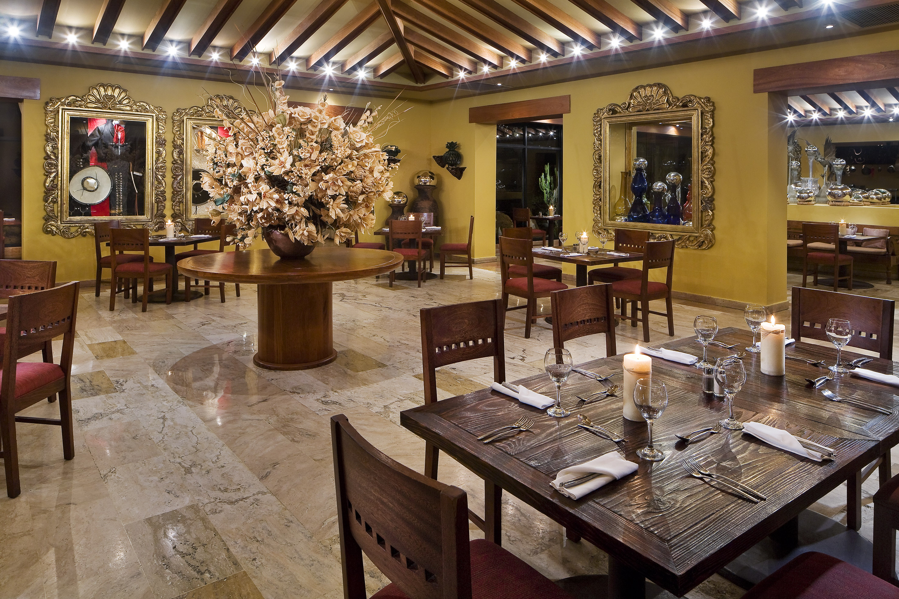 Elegant restaurant dining room with set tables, floral centerpiece, and wall art.