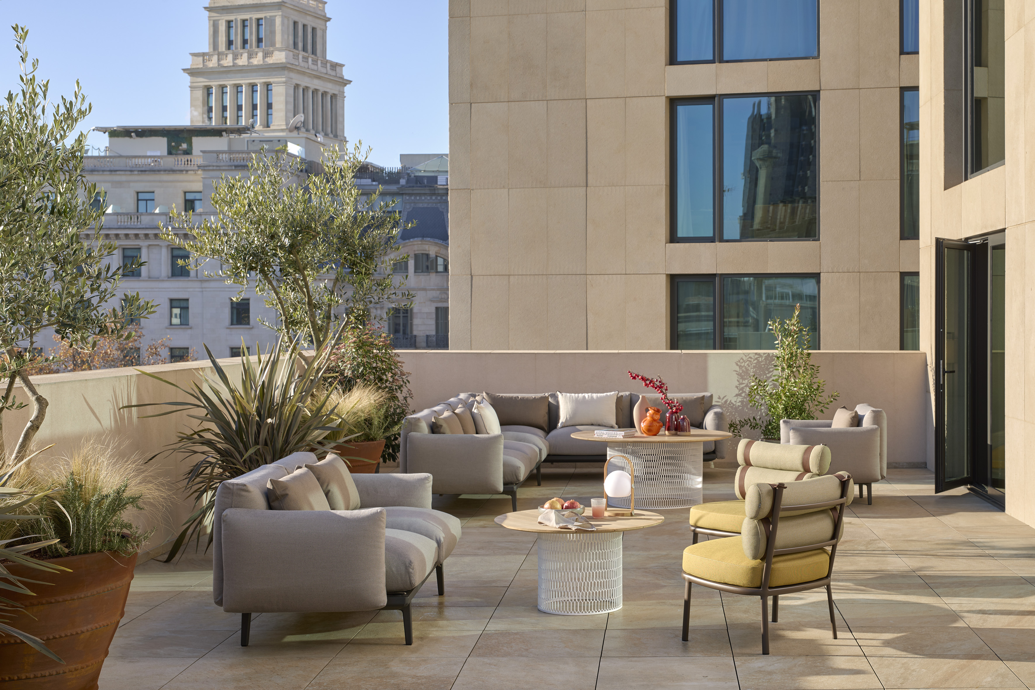 Stylish outdoor lounge furniture on a sunny urban rooftop terrace.