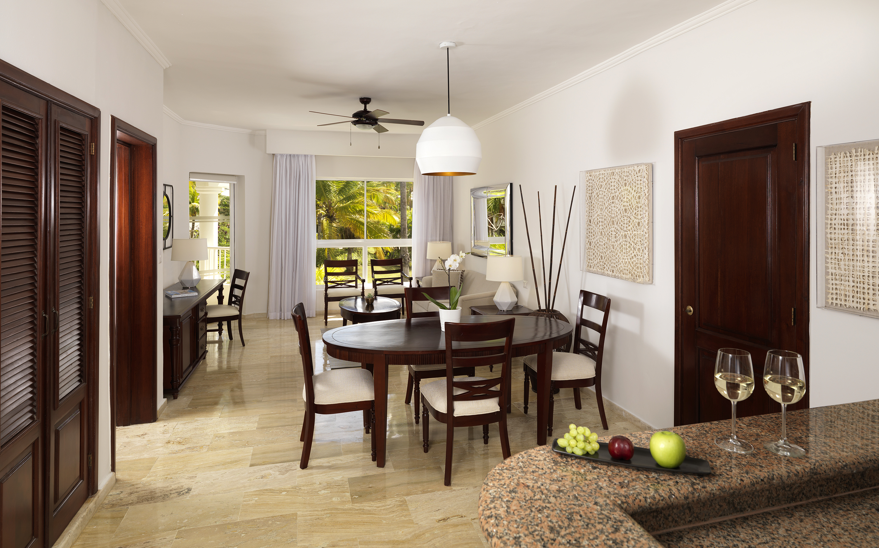 Elegant hotel suite living and dining room with tropical view.