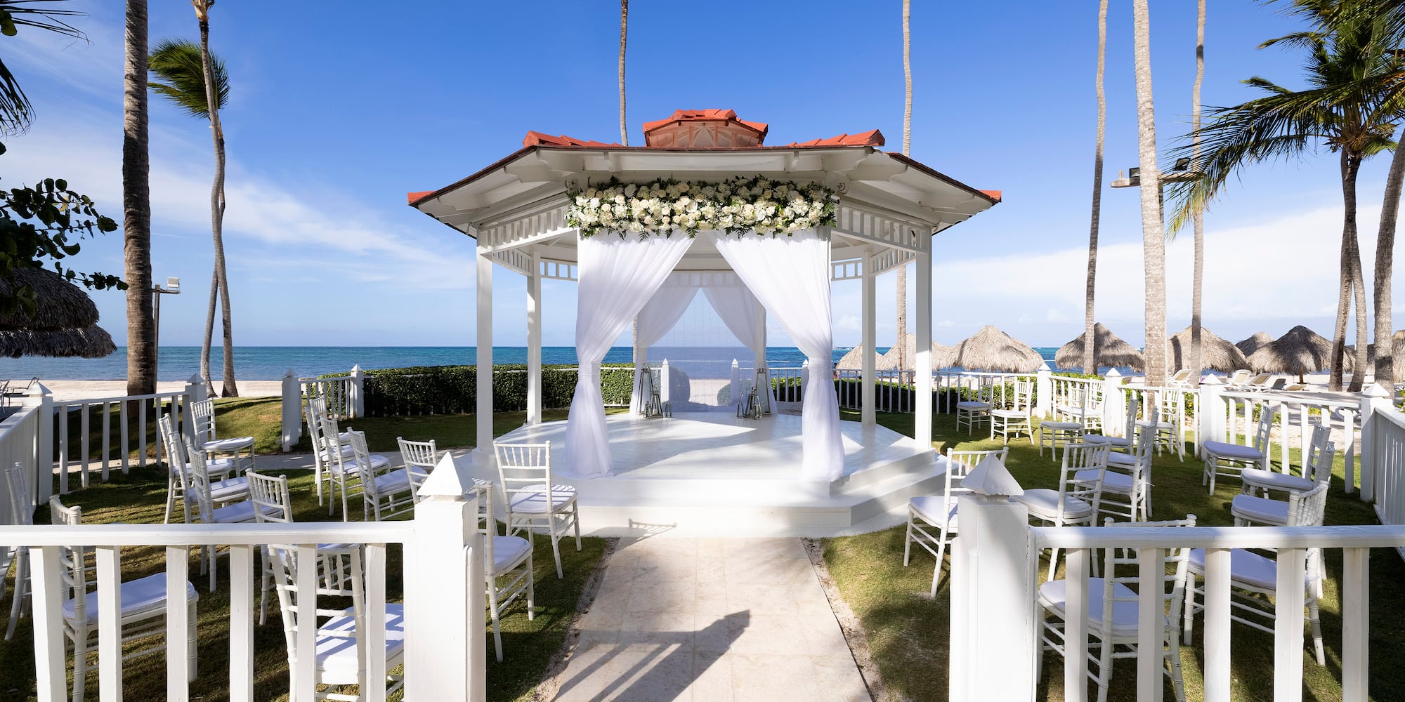 a white gazebo with white chairs and flowers on it