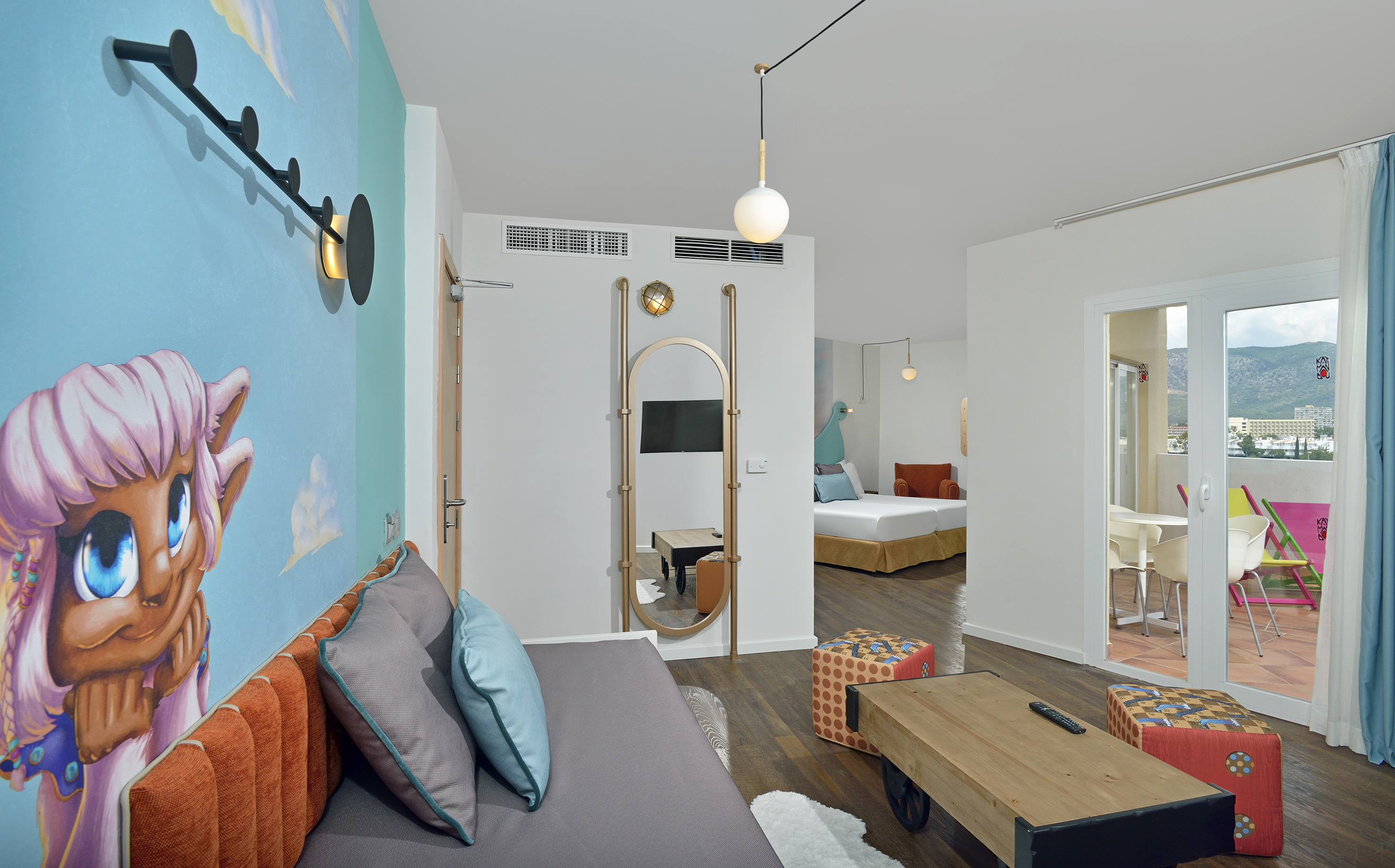 Family hotel suite: cartoon pony mural, sofa, twin beds, balcony mountain view.