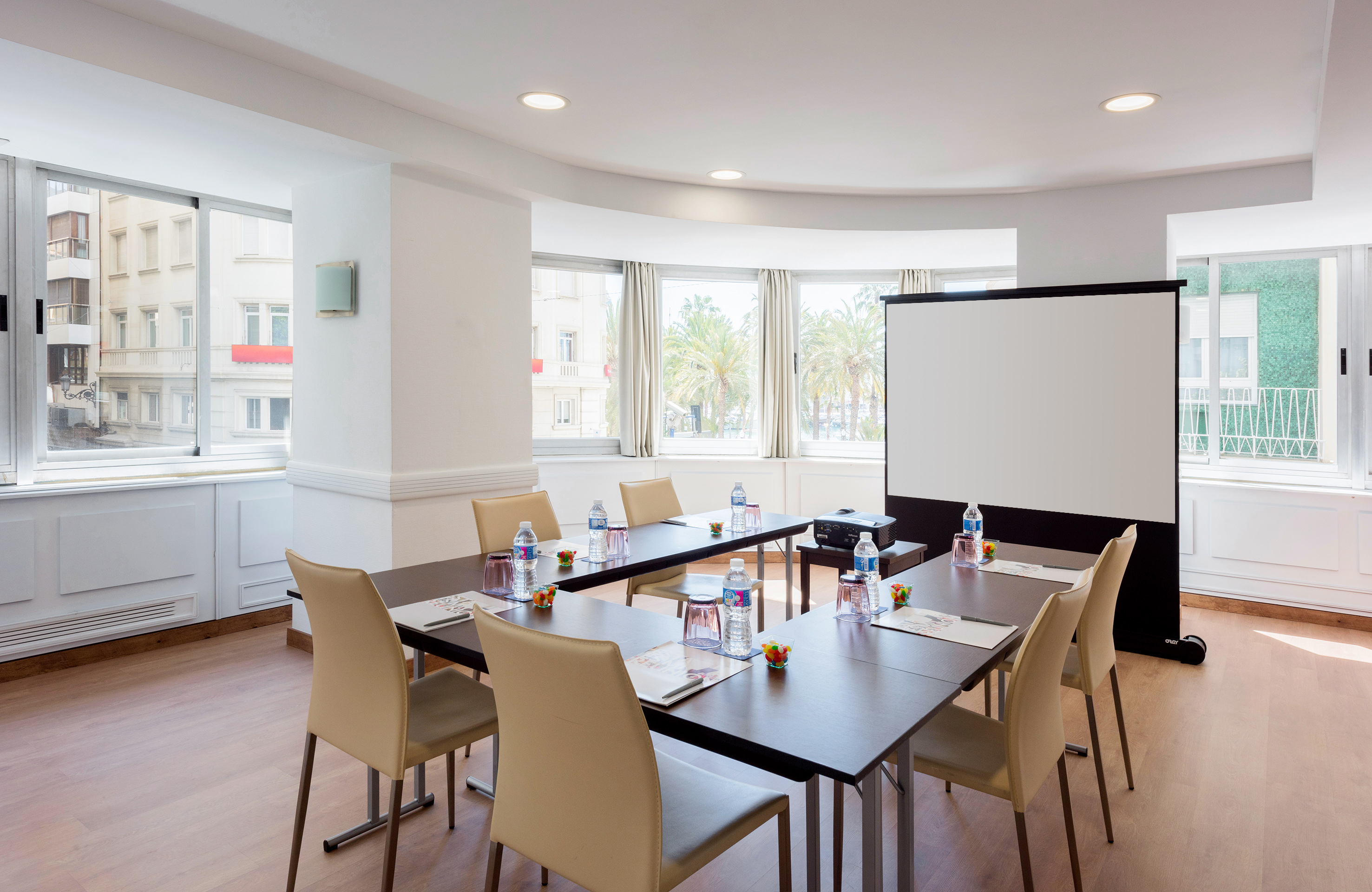 Bright conference room with tables, chairs, projector screen, natural light. - Tabarca - Hotel Alicante Gran Sol Affiliated by Meliá, 阿利坎特