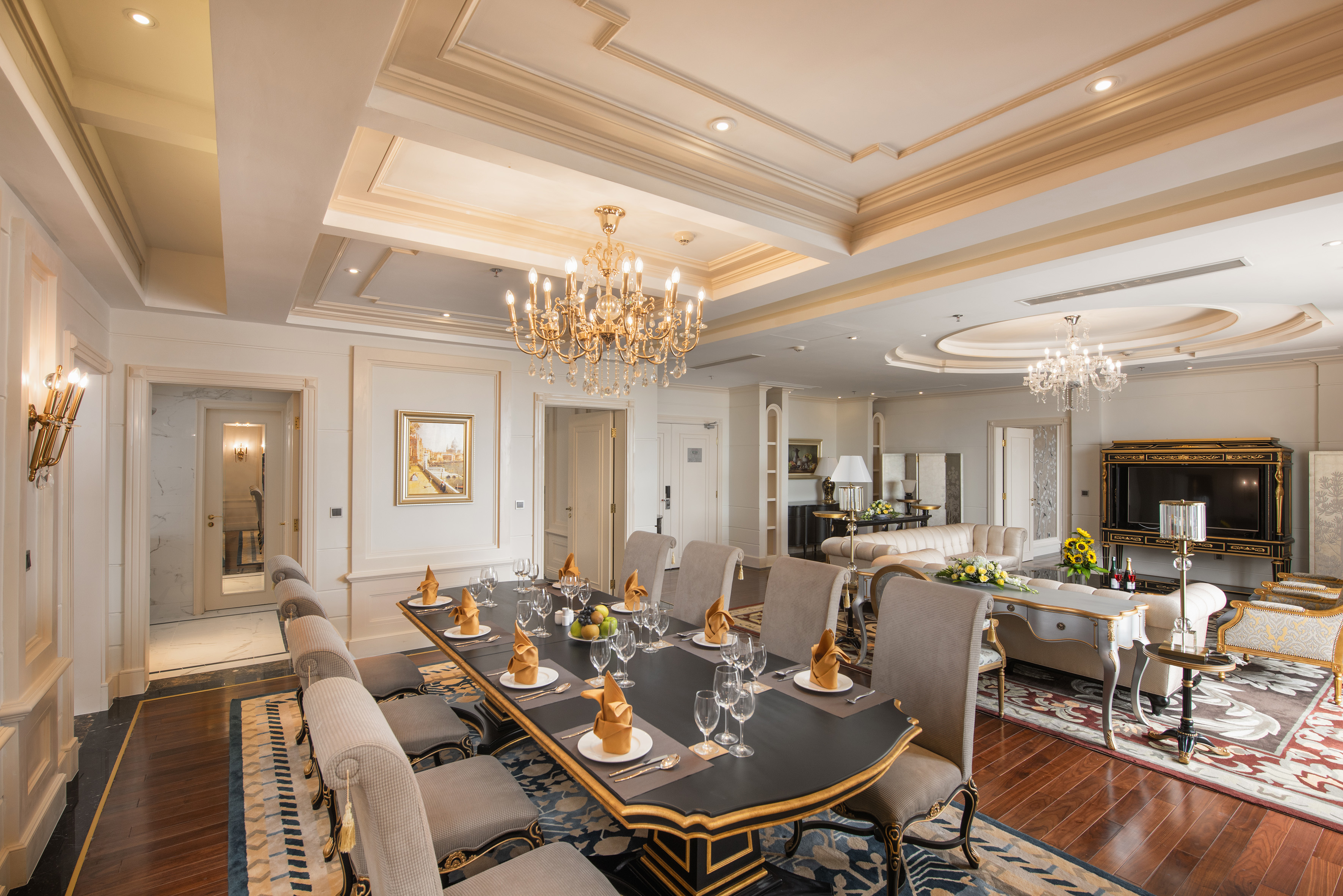 Luxurious dining and living room with grand chandelier and formal table setting.