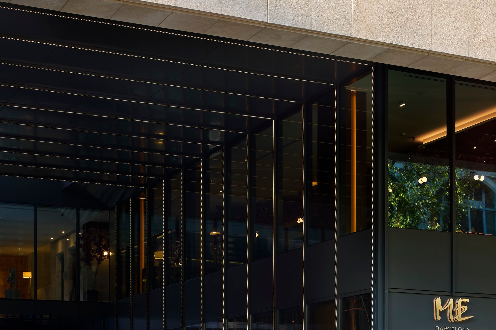 Mercedes-Benz van at sleek ME Barcelona hotel entrance with glass facade.