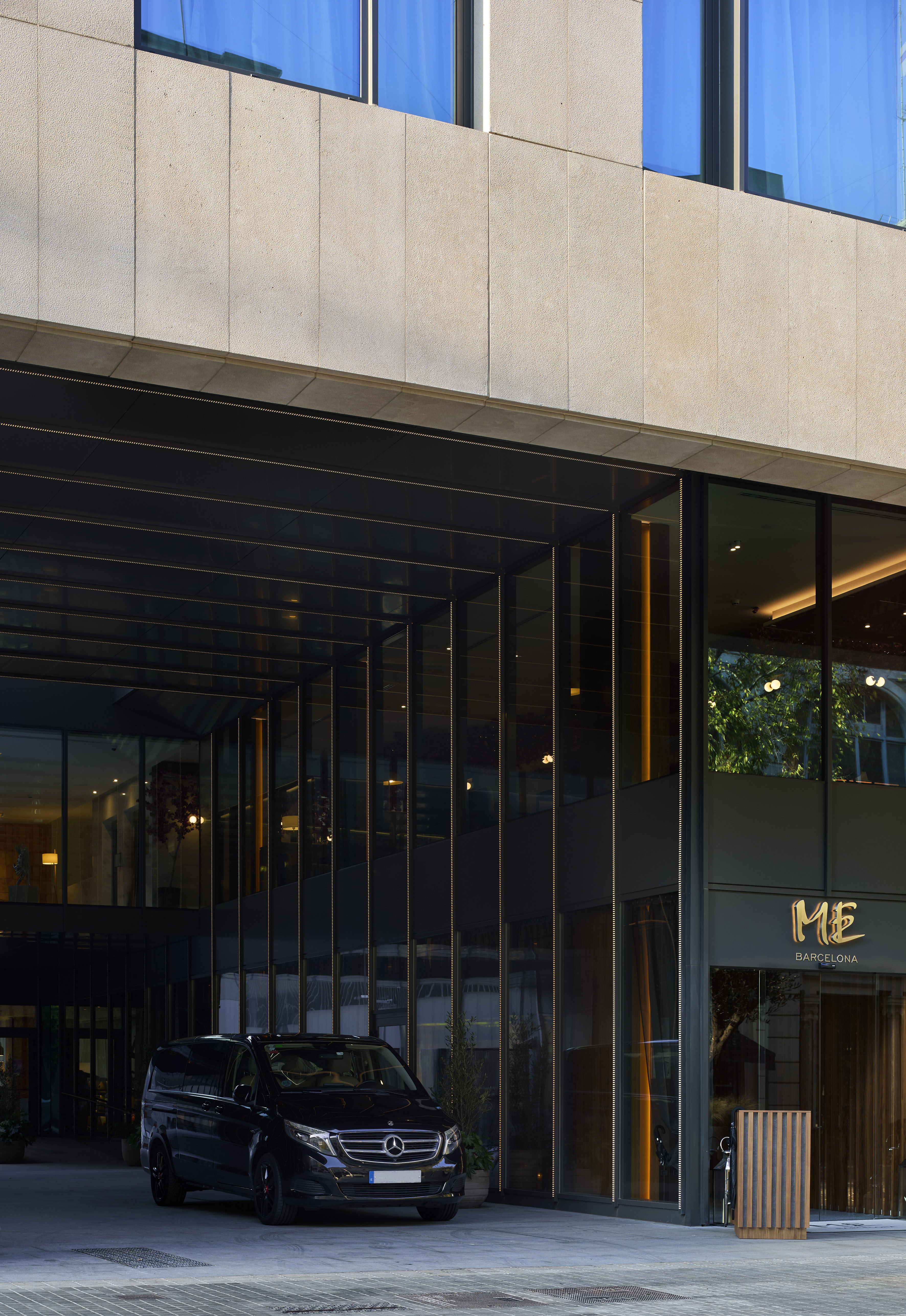 Mercedes-Benz van at sleek ME Barcelona hotel entrance with glass facade.