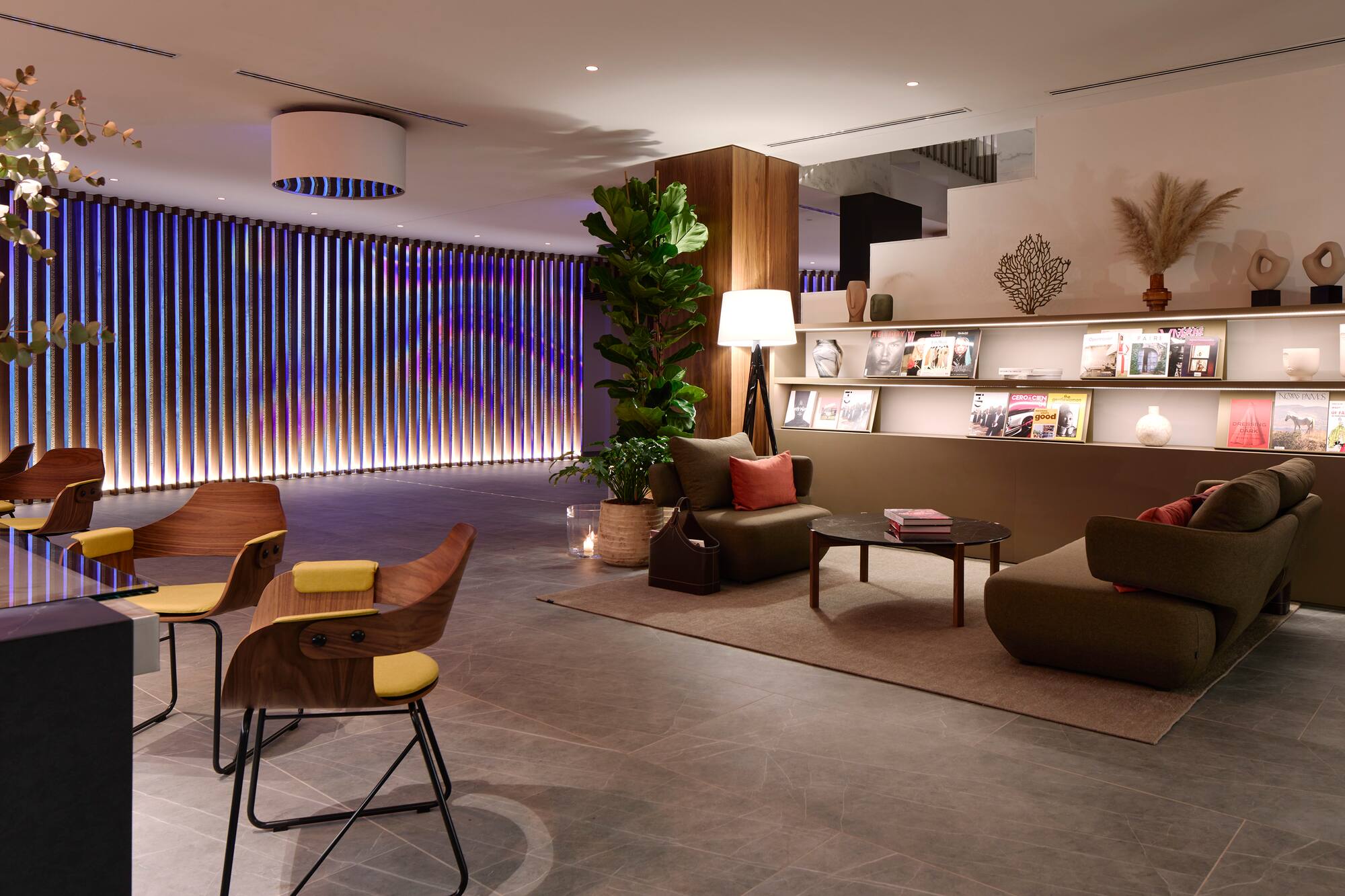 Modern lounge with stylish seating, accent lighting wall, and magazine display.
