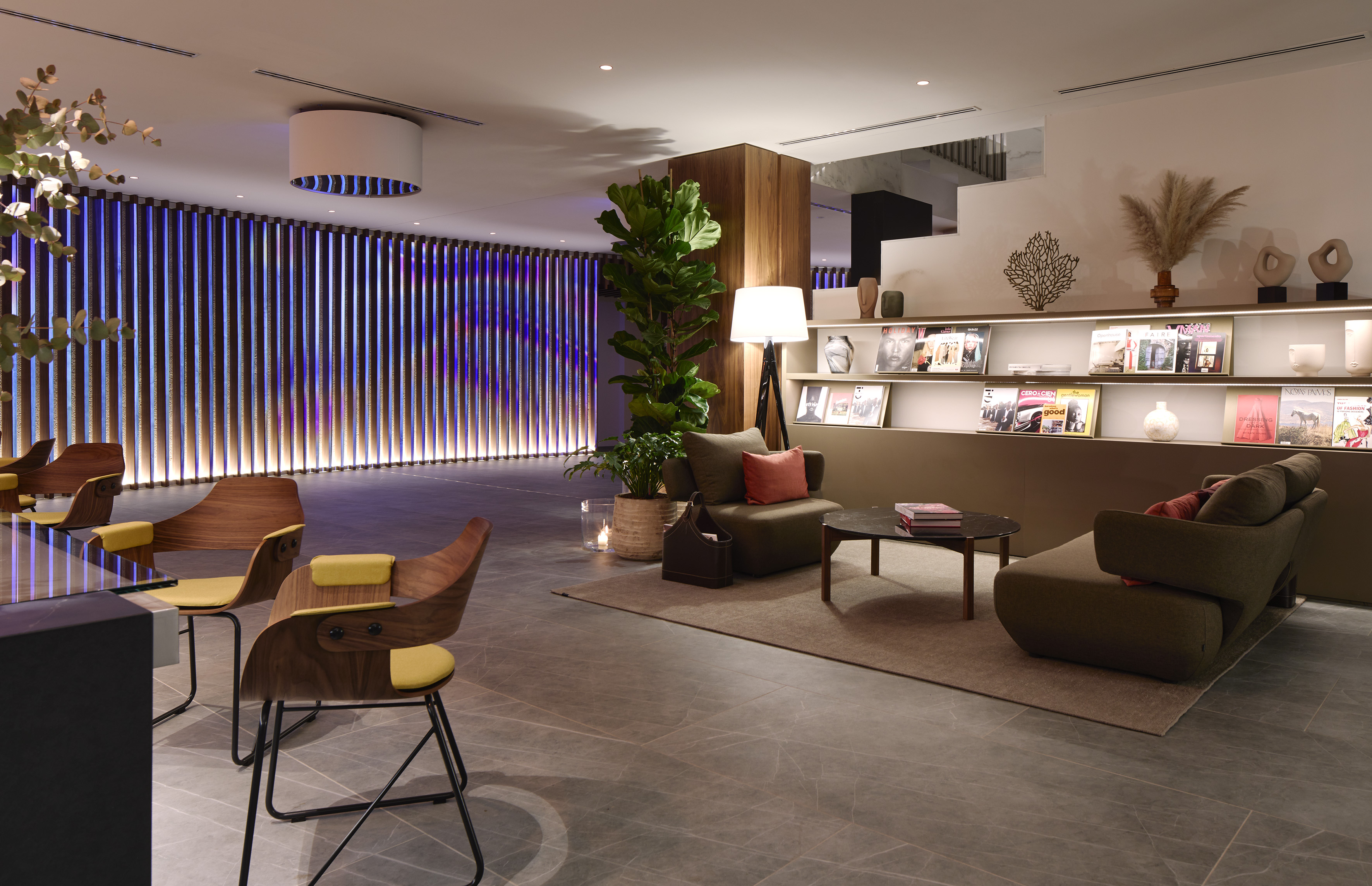 Modern lounge with stylish seating, accent lighting wall, and magazine display.