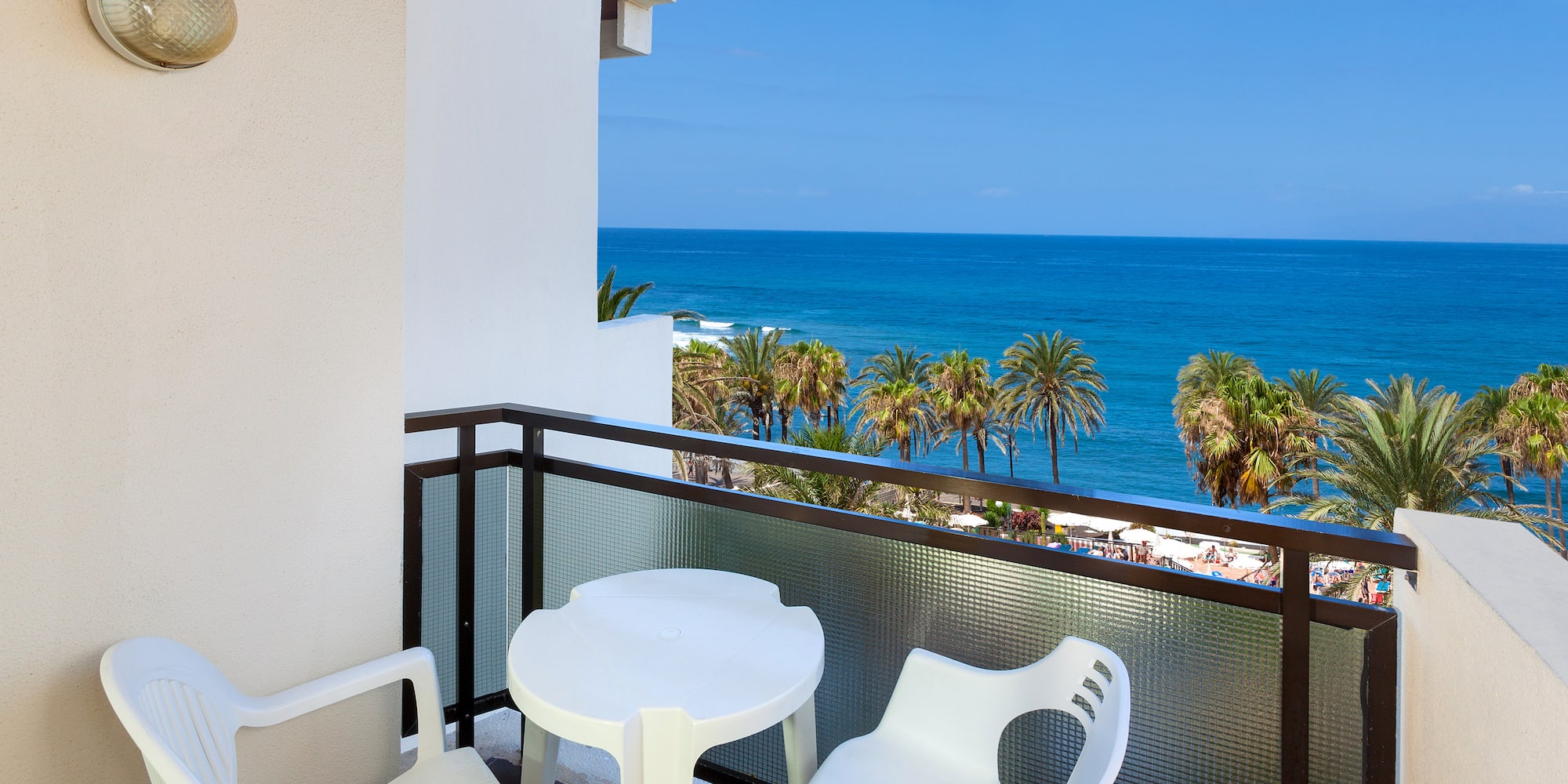 a balcony with chairs and a table overlooking the ocean