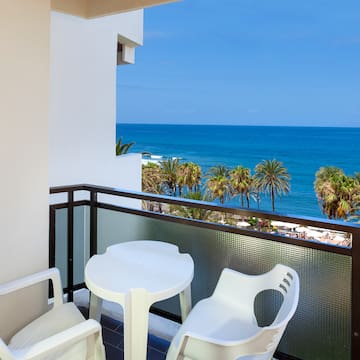 a balcony with chairs and a table overlooking the ocean