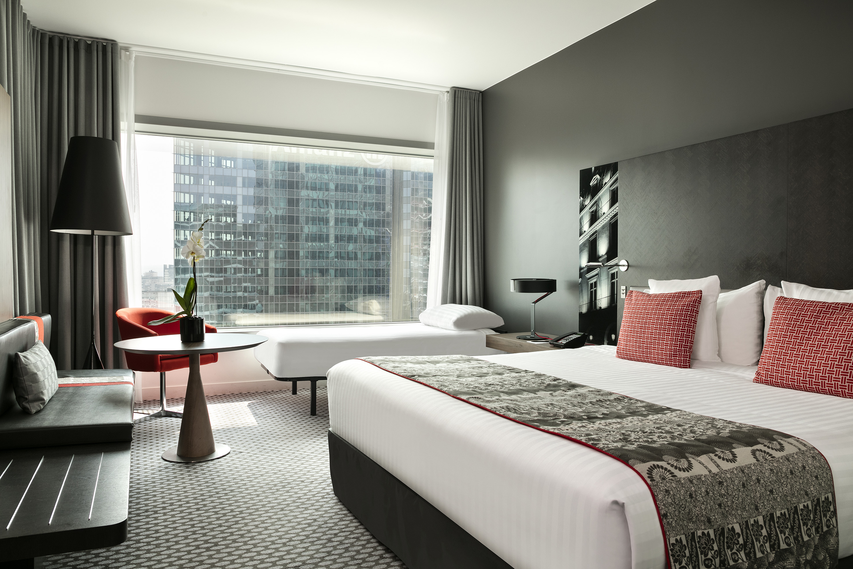 Luxurious hotel room with king bed, modern decor, and large city view window.