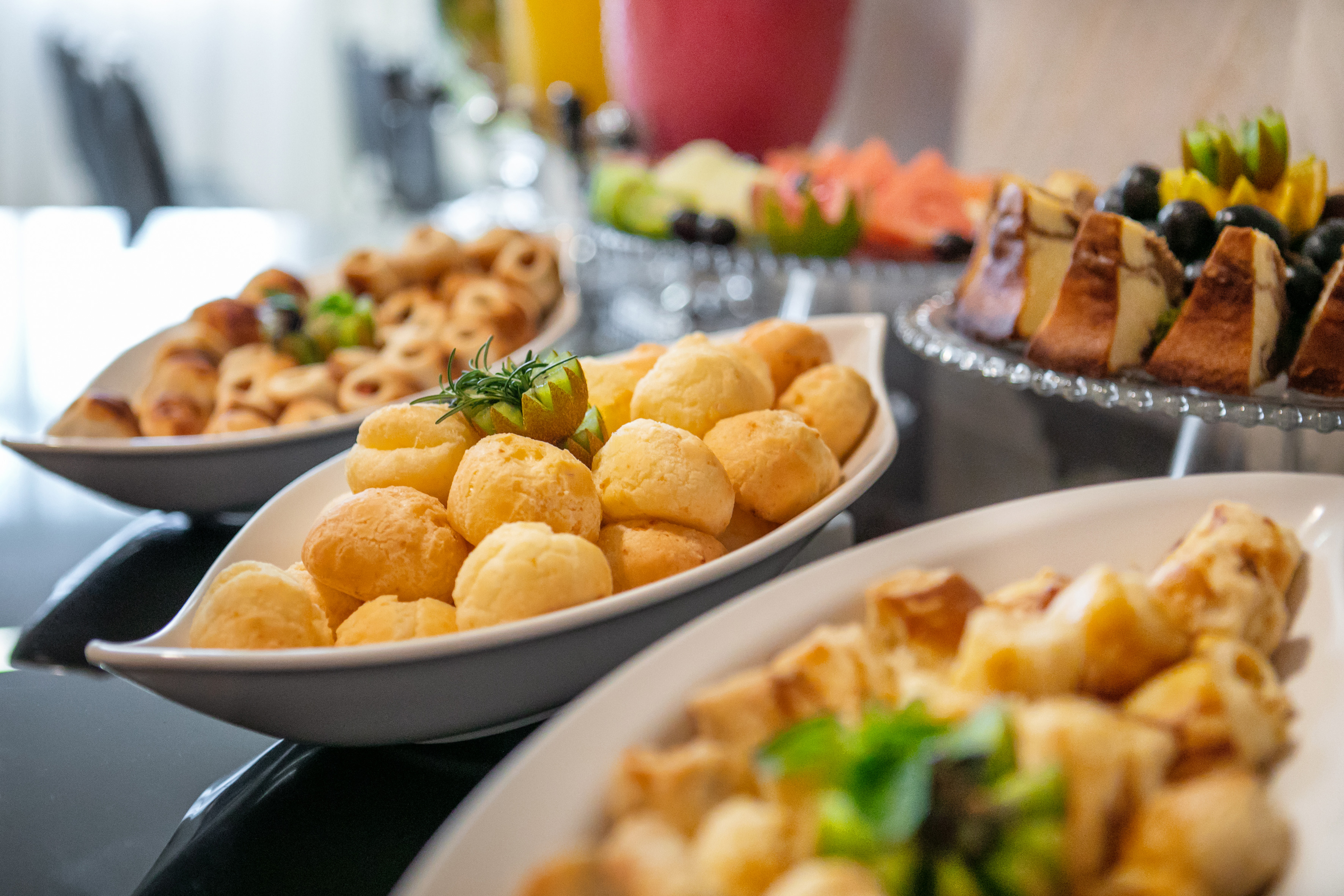 Golden Pão de Queijo cheese bread with rosemary, part of a breakfast buffet.